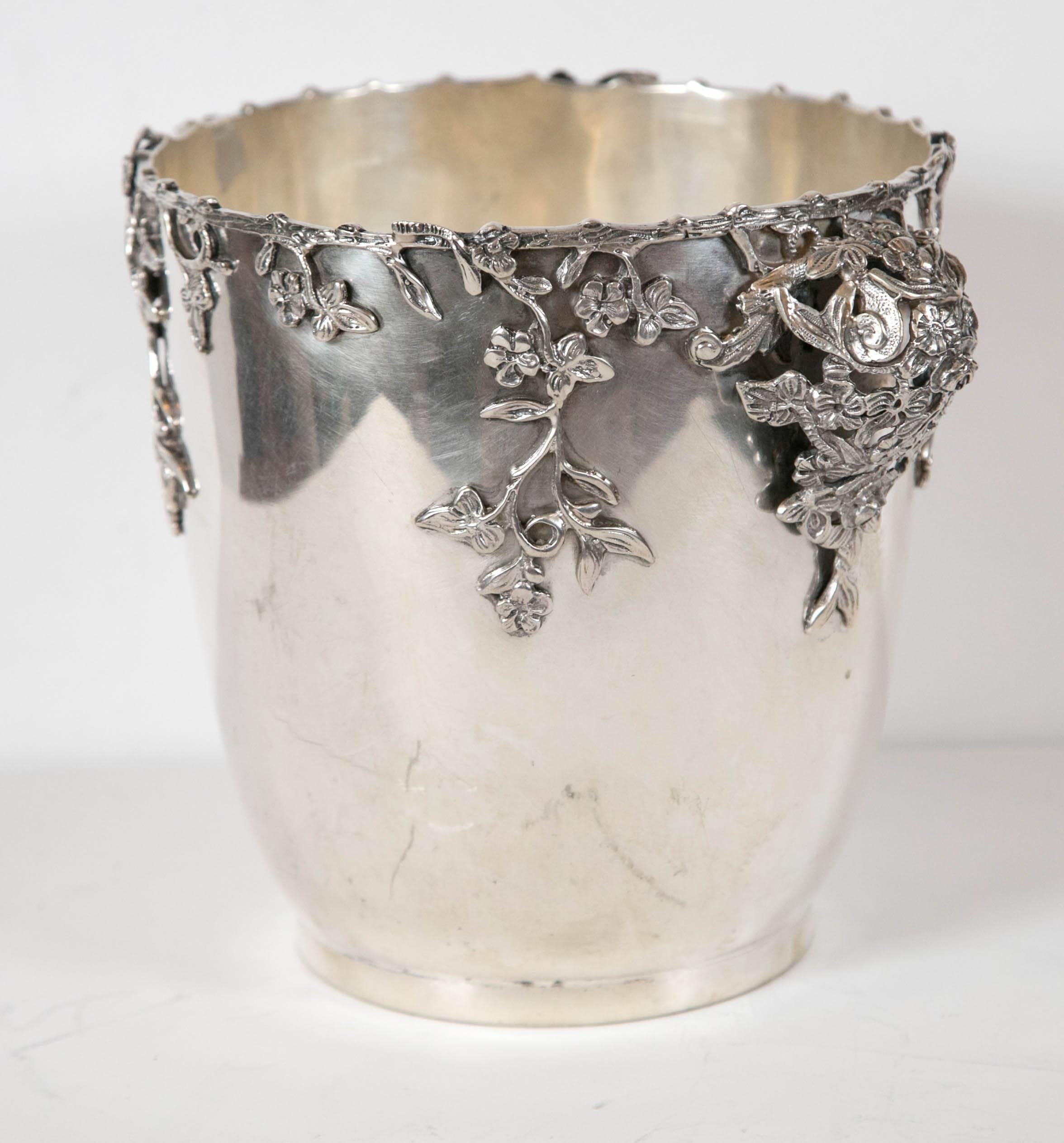 An Italian 800 silver wine cooler adorned with leaves and vines that lead to intricate handles made up of intertwining foliage and flowers. The bottom is marked Lavorazione a Mano (handmade).