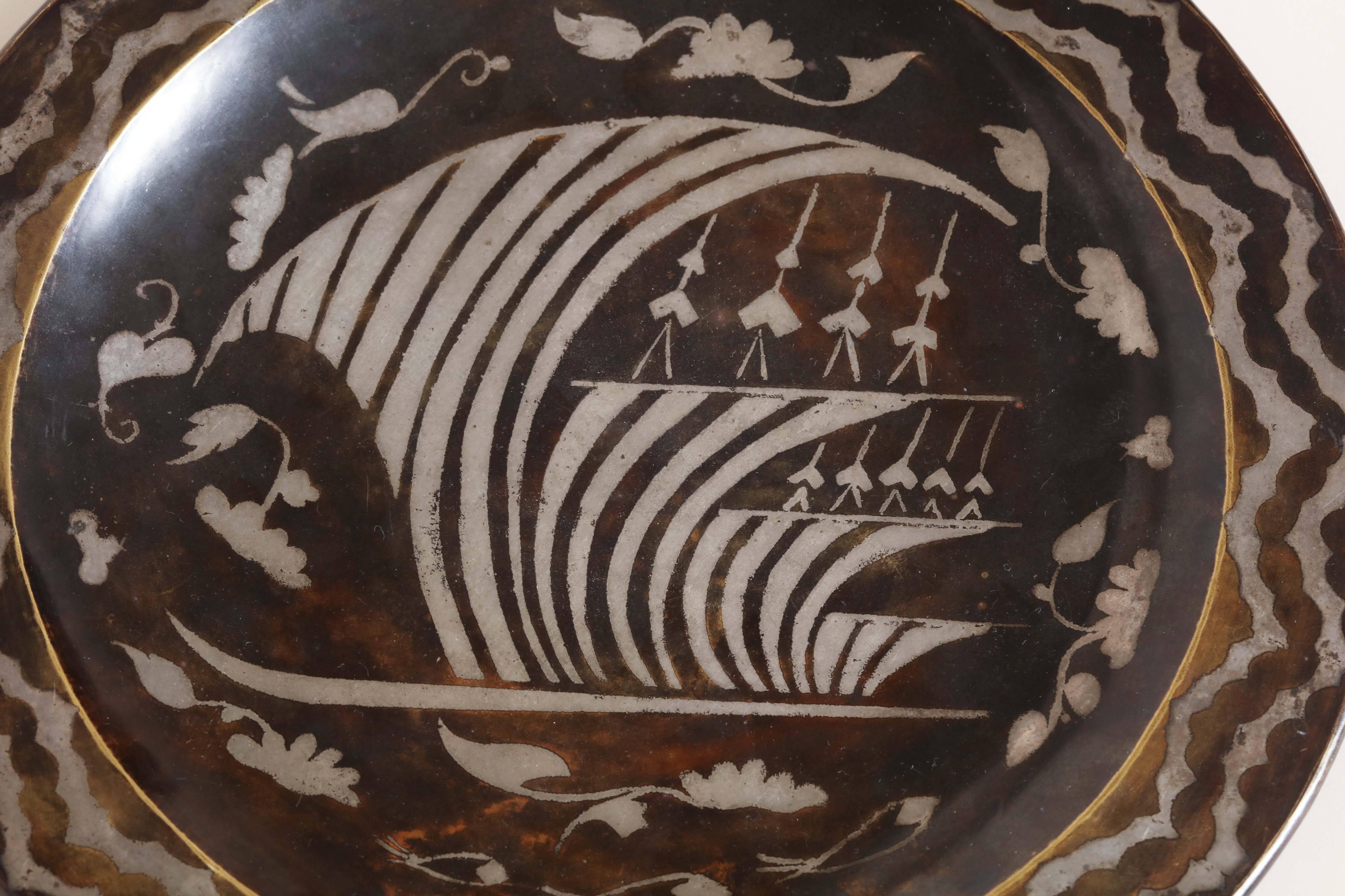 Dinanderie brass plate with inlaid silver design of sailing ship on stylized waves. 

Unidentified monogram bif underneath.

(Price shown is reduced price, no further trade discount) 
