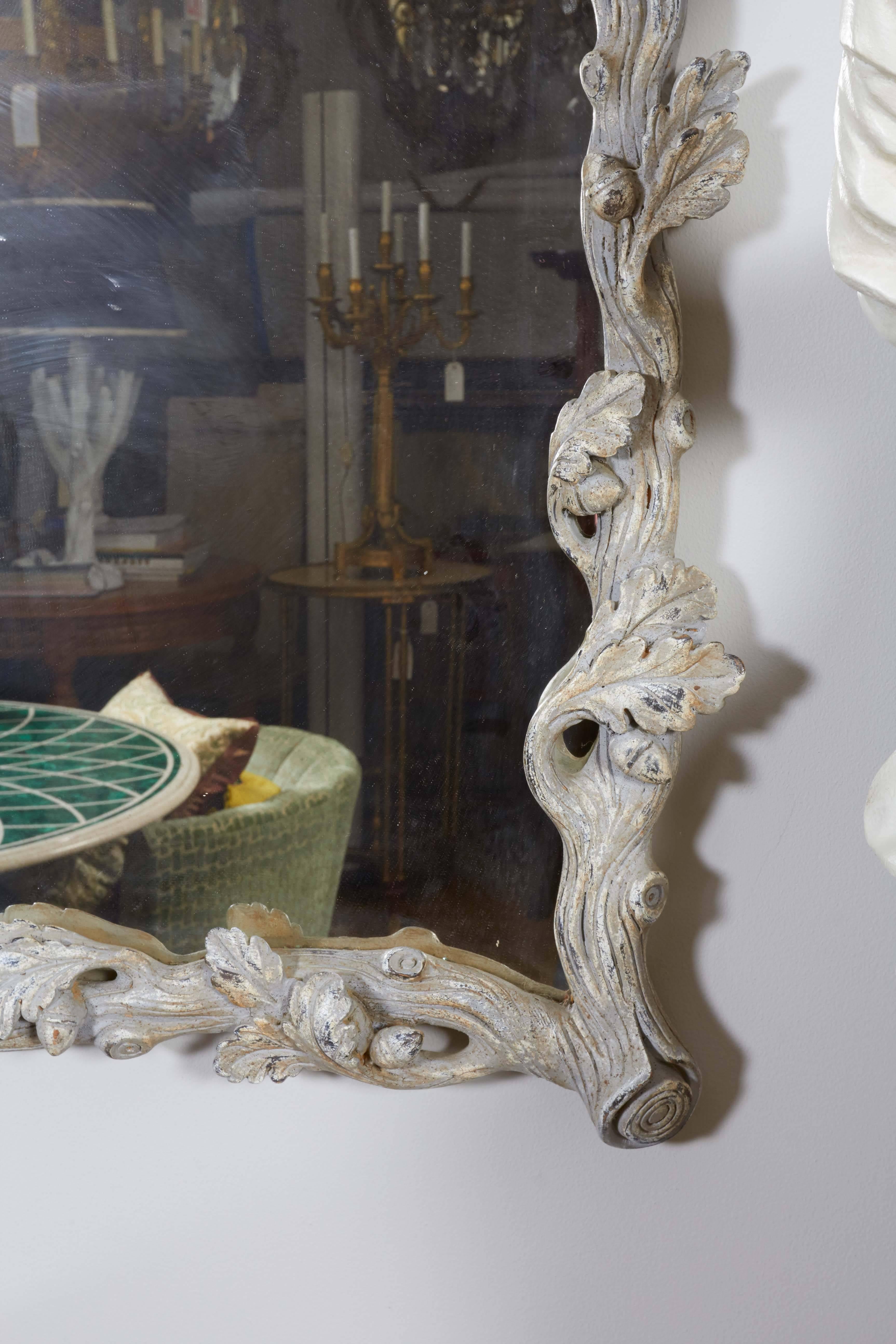 An Italian rococo style faux bois mirror with painted grey finish, hand-carved foliate detail throughout.