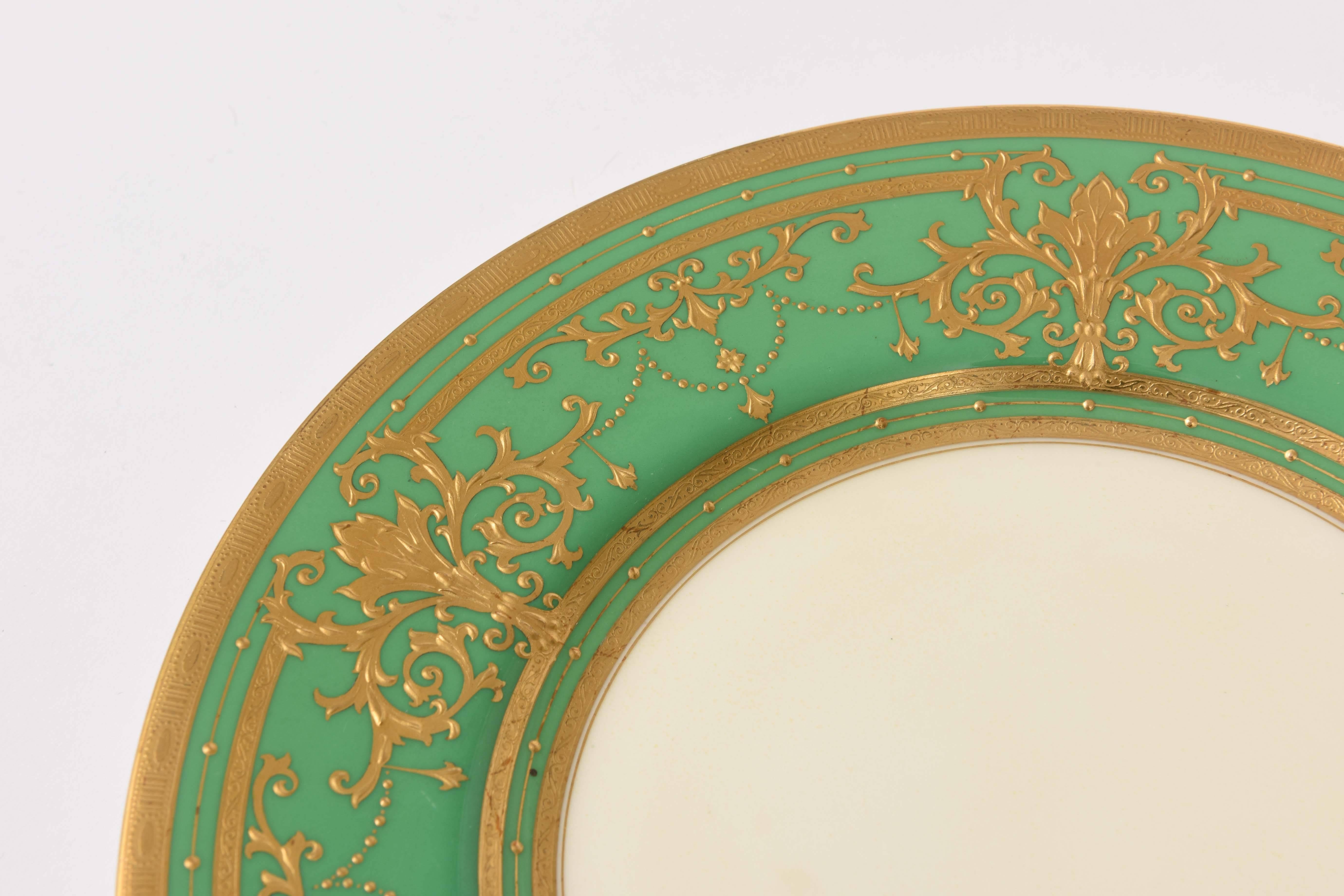 A custom ordered set by the world re known firm of Minton, England featuring raised paste gilt foliate design on a rich green shoulder. This set is in wonderful antique condition and has a nice clear center and the added gilt backed rim of plate.