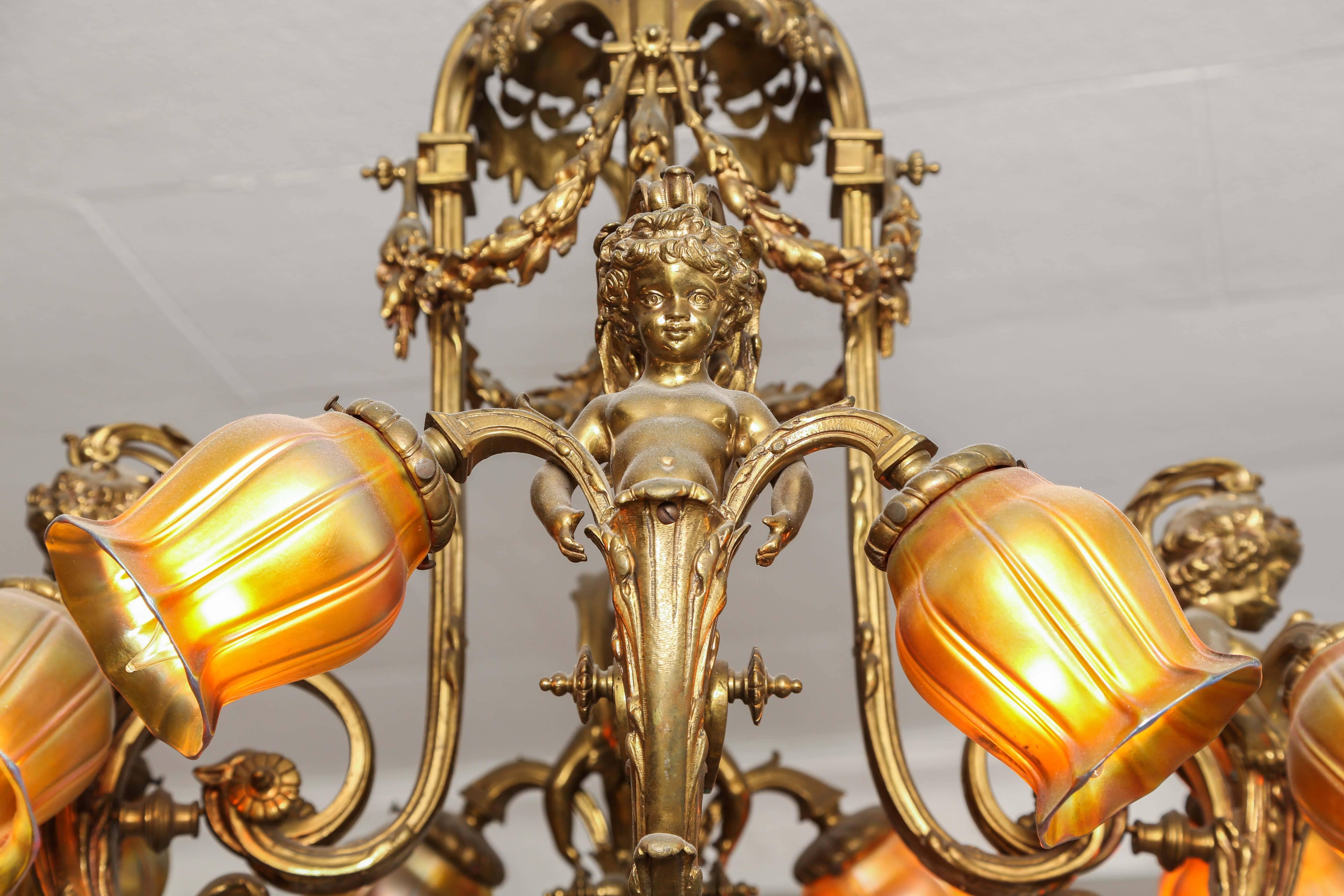 A gorgeous (and heavy) nicely hand chased gilt bronze eight-arm chandelier with art glass shades dating to the last quarter 19th century. Please note the detail on the figural cherubs or putti as well as the garlands of flowers. A lovely designed