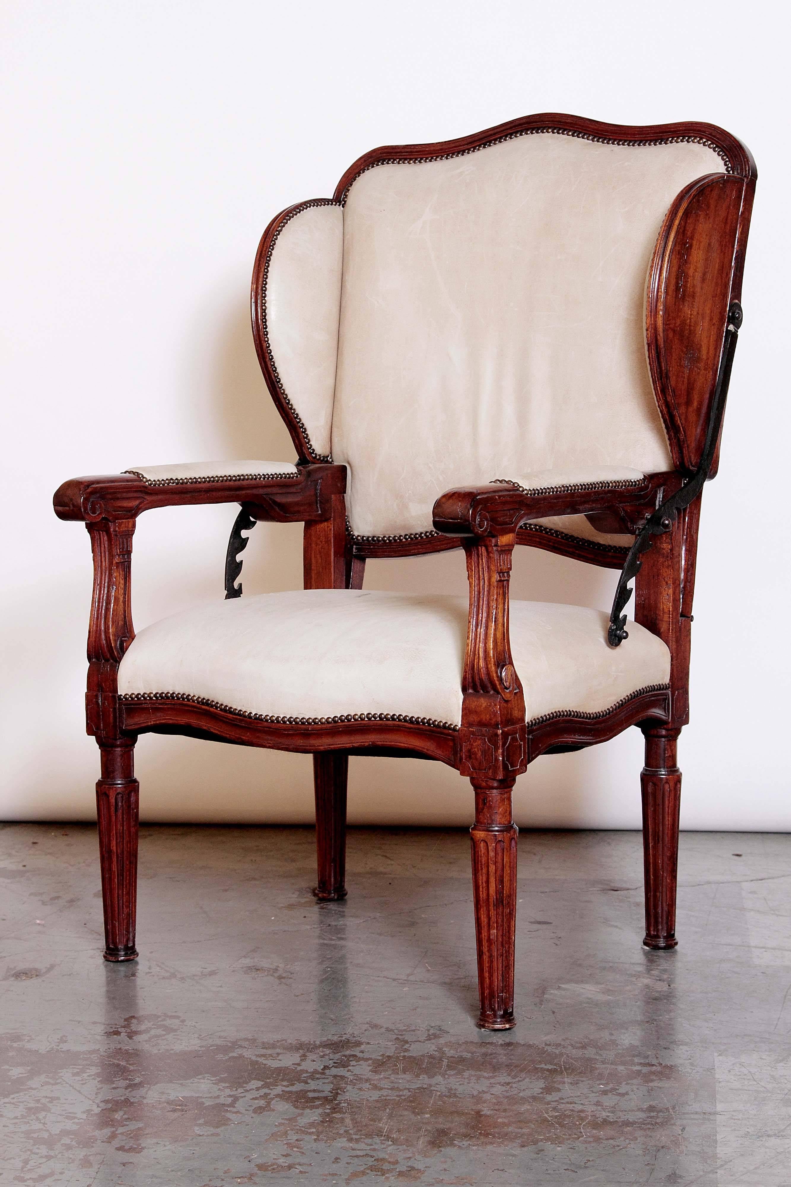 A rare and wonderful French reclining wingback armchair.

Of very generous scale, the armchair is upholstered in light buff leather, with nailhead trim.

The reclining ratchet mechanism, hinges, and brackets are of darkened steel.

A truly