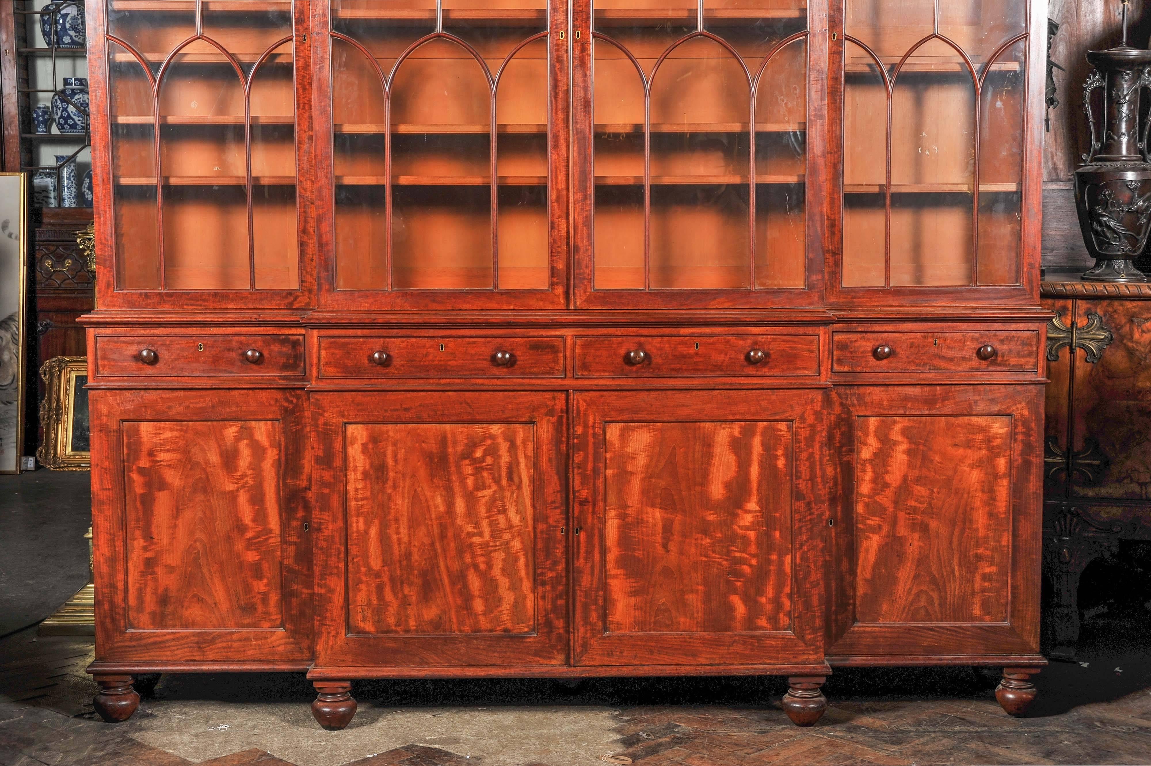 A very good quality Regency period mahogany break fronted library bookcase, in the manner of Gillows. Having four Gothic astrical glazed doors, each with adjustable shelves. Four mahogany lined frieze drawers above four panelled doors enclosing