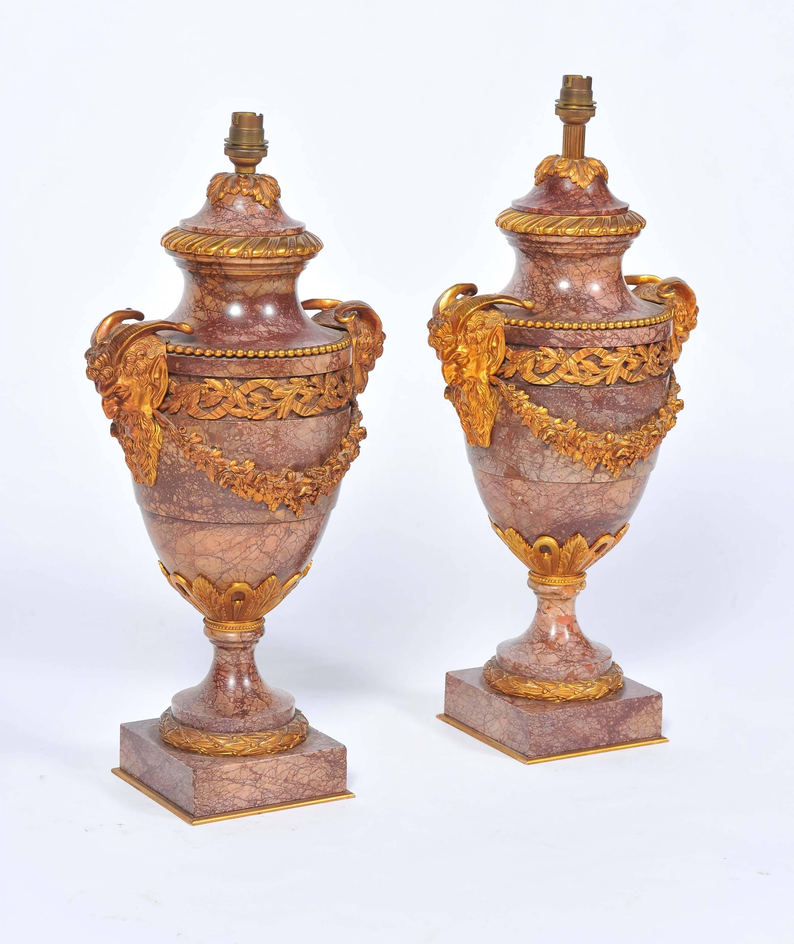 A good quality pair of French Louis XVI style marble and gilded ormolu vases / lamps. Having classical ram's head mounds and ribbon and foliate swag decoration.