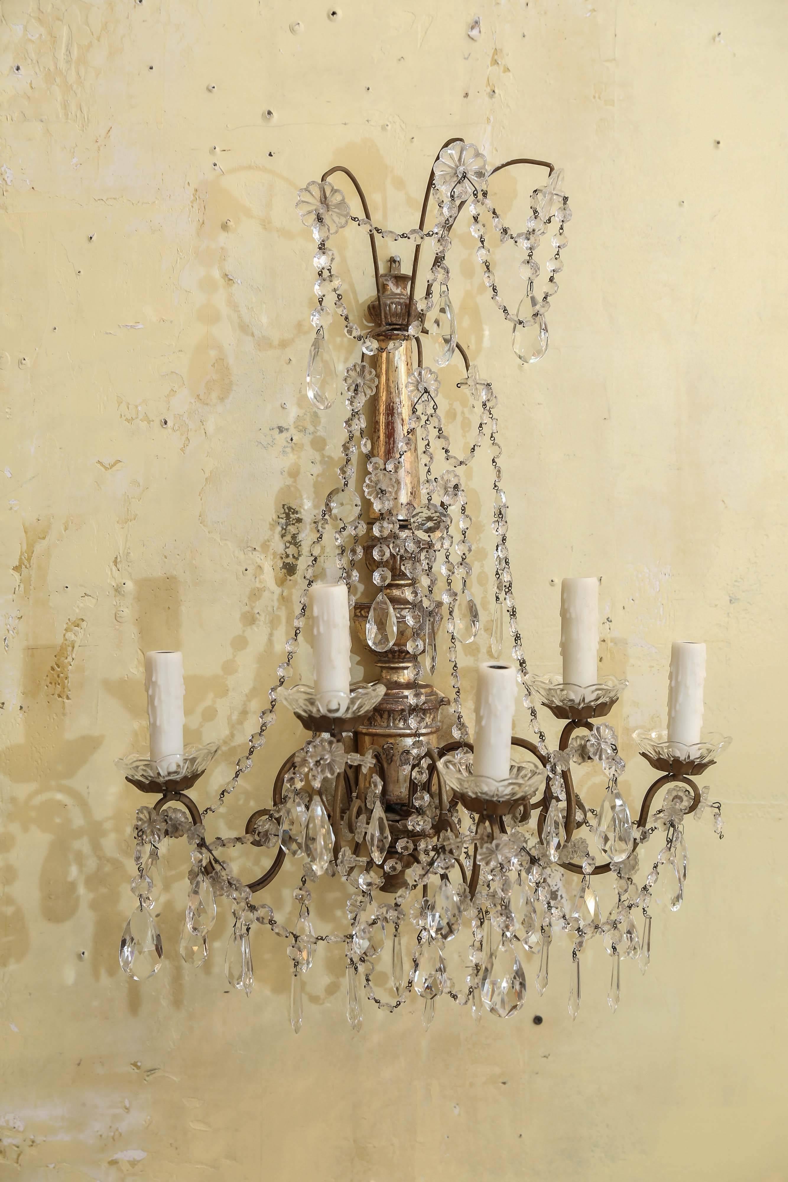 Pair of Italian sconces decorated in crystal prisms. Hand carved giltwood sconces from Genoa, Italy, are circa 1920-1940. Each sconce features five arms, newly wired for use within the USA. Sold together and priced as a pair for $4,800.