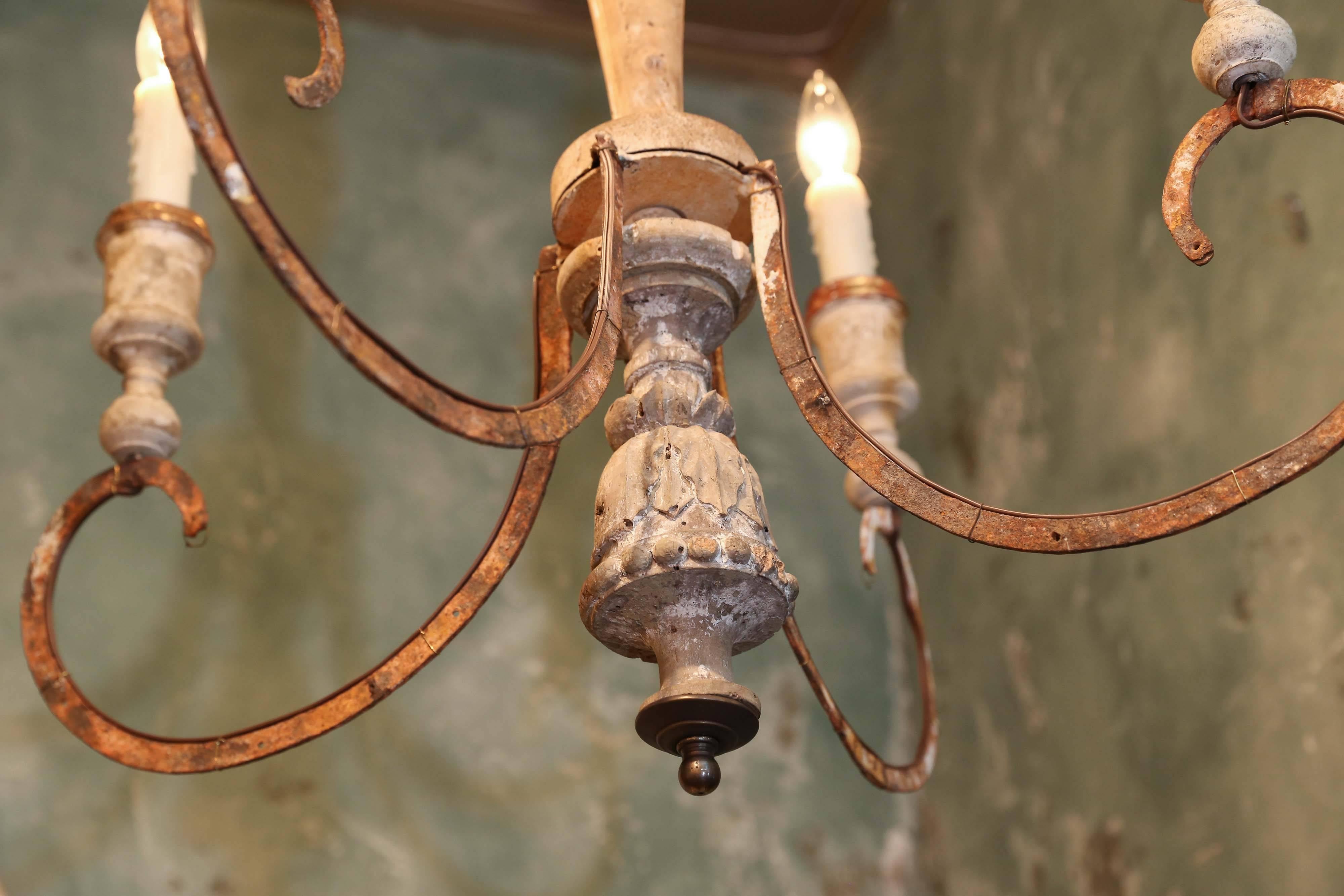 Iron and wood chandelier, newly-wired, with four candelabra-sized lights, for use within the USA. Fashioned from antique French carved wood fragments and later elements. Included chain, a canopy and bracket for mounting into the ceiling.