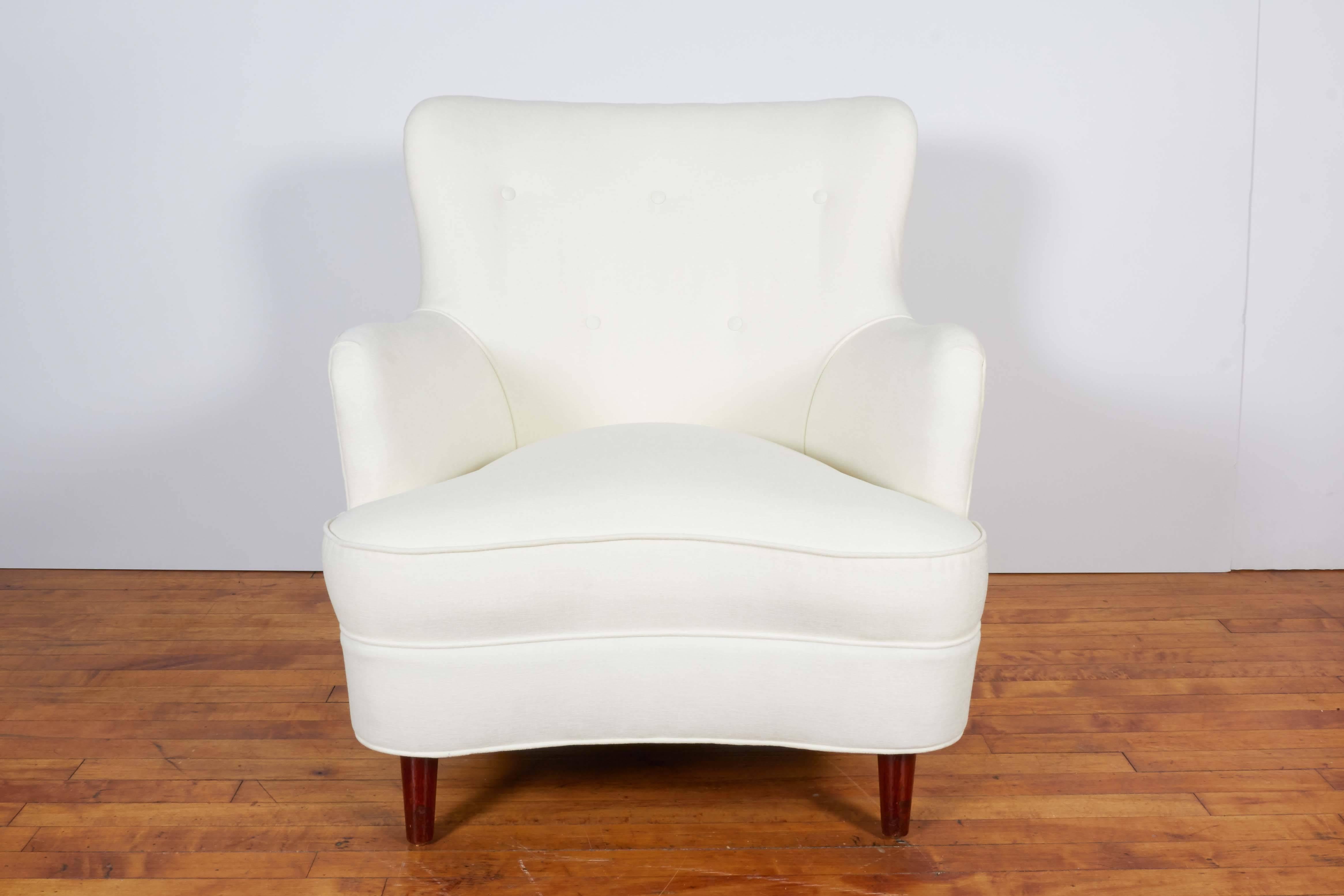 A pair of wingback armchairs, manufactured in Italy circa 1950s, each entirely upholstered in white chenille, with button tufted detail to back, on tapered wood legs. Very good vintage condition, consistent with age; newly reupholstered.