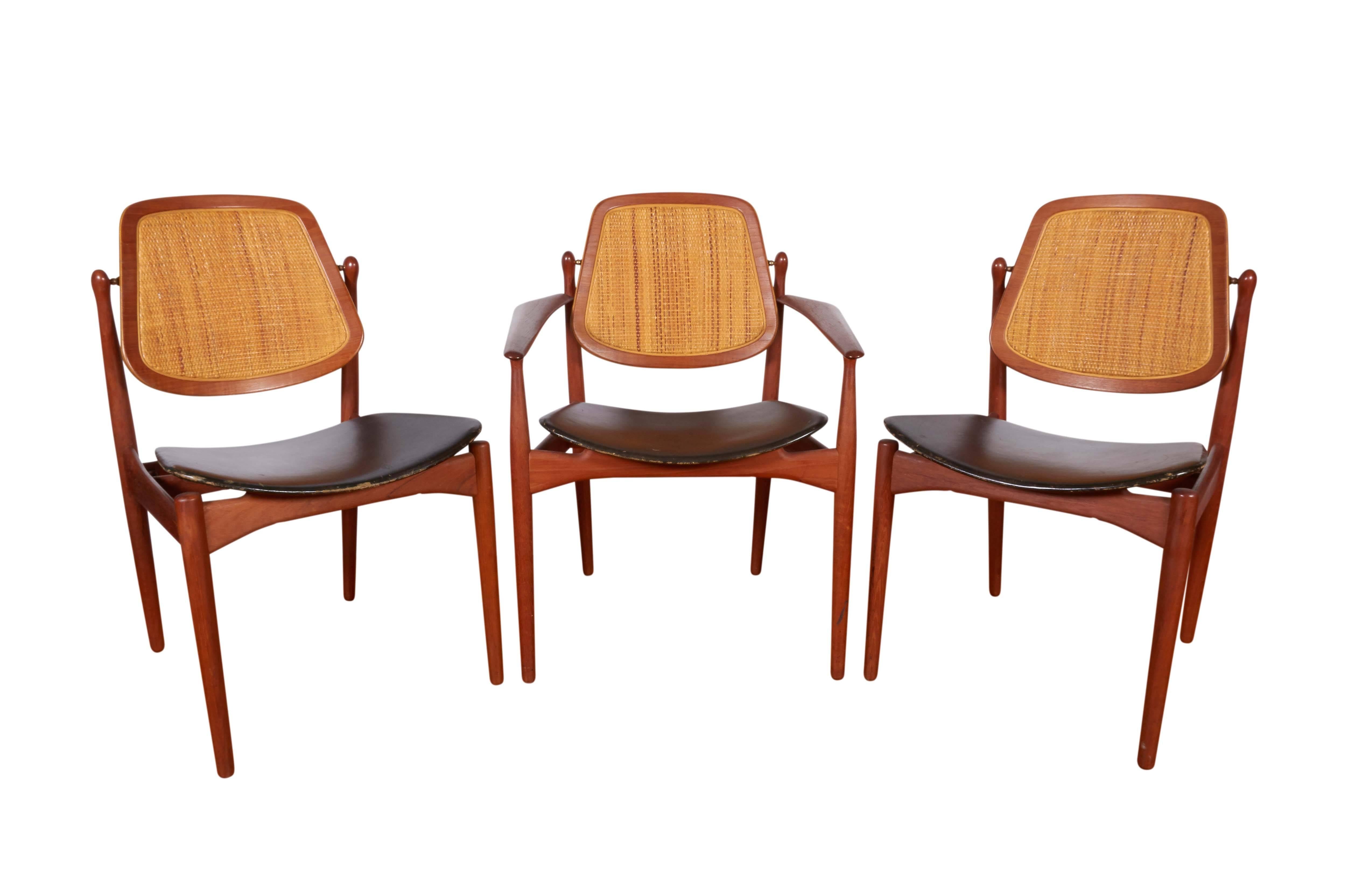 A set of six Scandinavian Modern dining chairs by Danish designer Arne Vodder, manufactured circa 1950s by France & Daverkosen (Later France & Son), comprising two armchairs and four side chairs, with pivoting cane backs and floating black leather