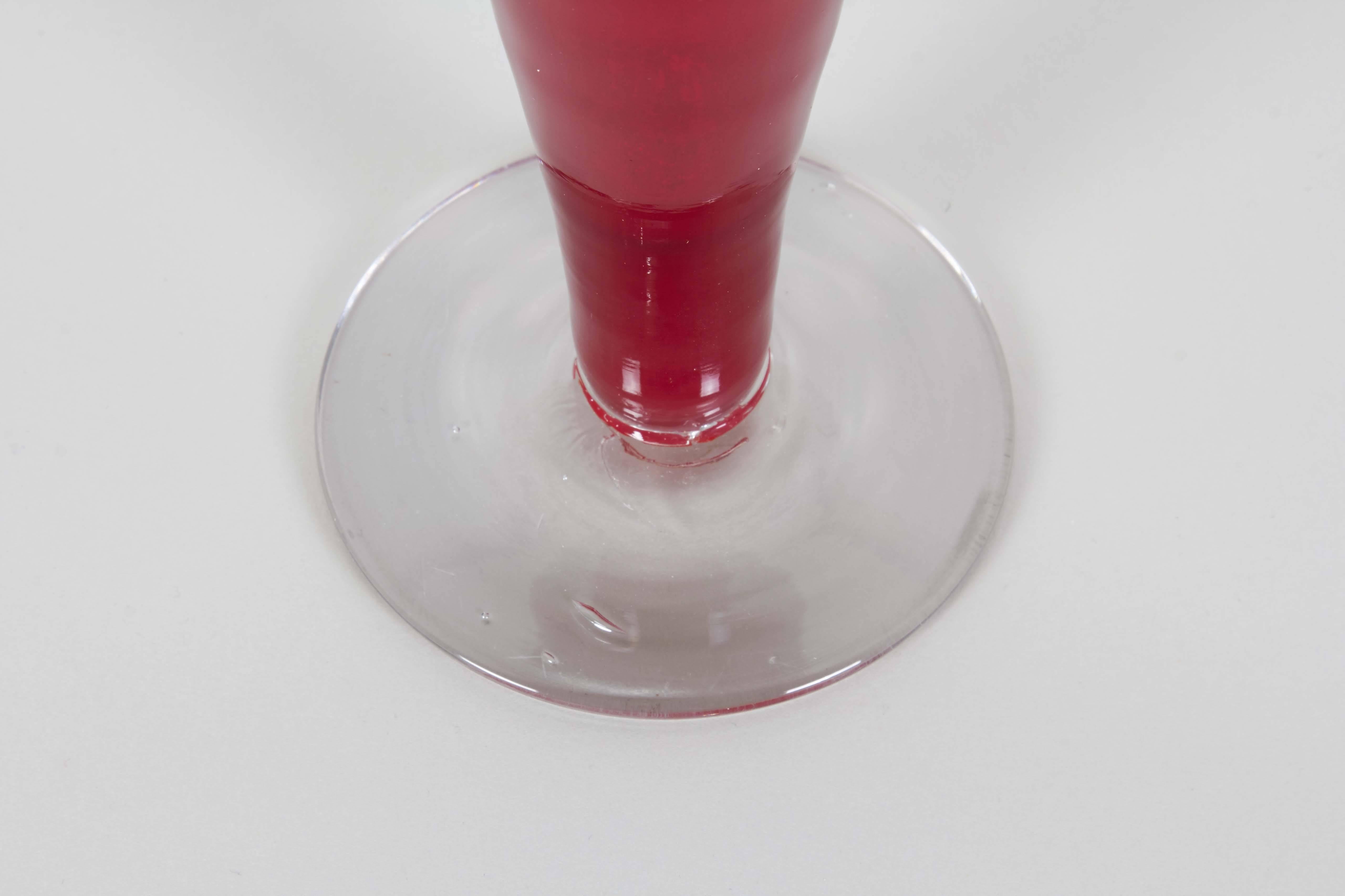 A decanter from the 'Regal' series by Blenko, production of which lasted from 1959-1962, comprised of bright red blown glass, pointed finial stopper with tapered body on clear circular base. Markings include [Blenko] acid etched to the underside of