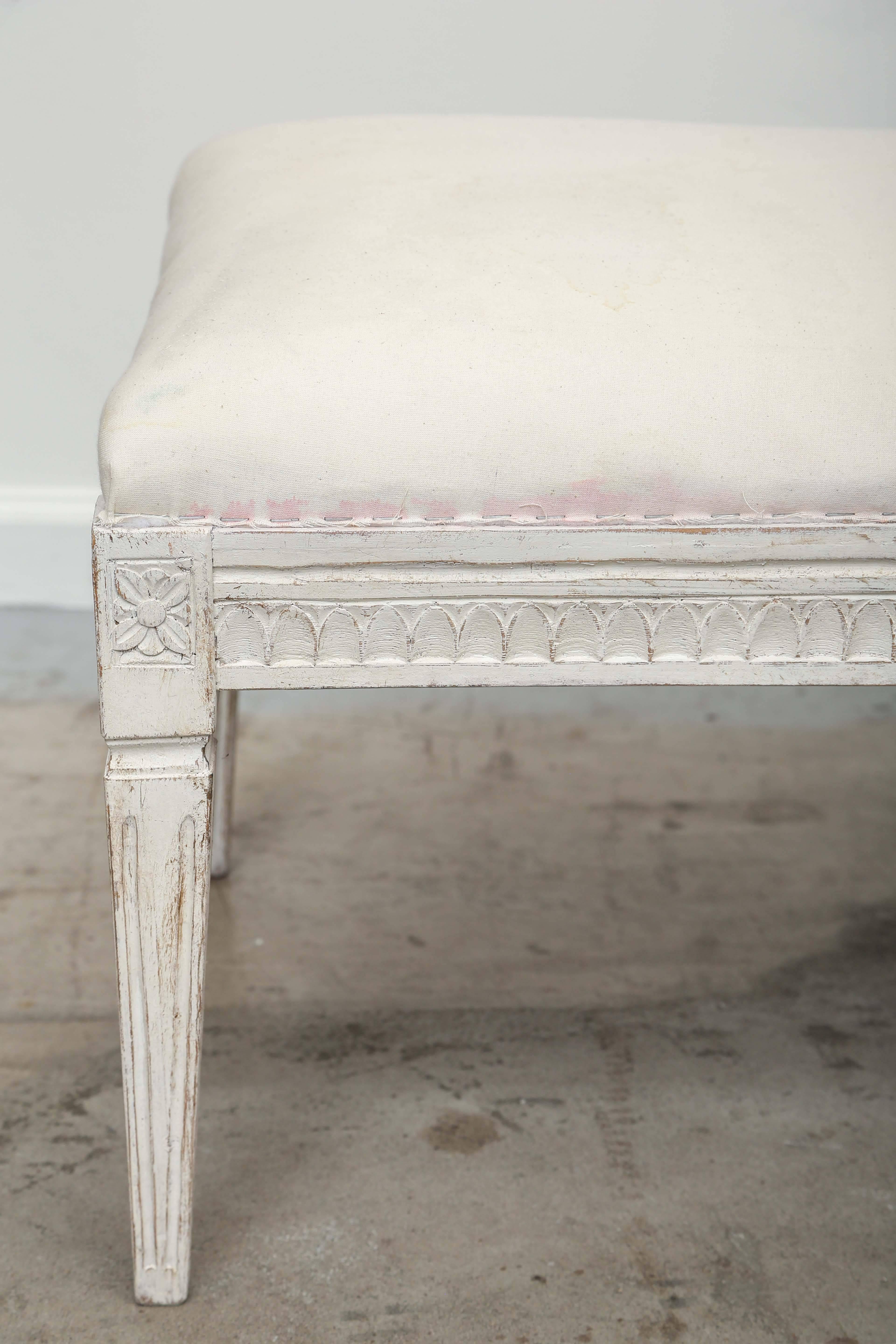 Antique Swedish Gustavian painted bench, with carved lamb's tongue apron, square tapered legs with carved flower rosettes at top of each leg.
The bench is painted in a white-greyish color and distressed finish curved upholstered top
mid-19th