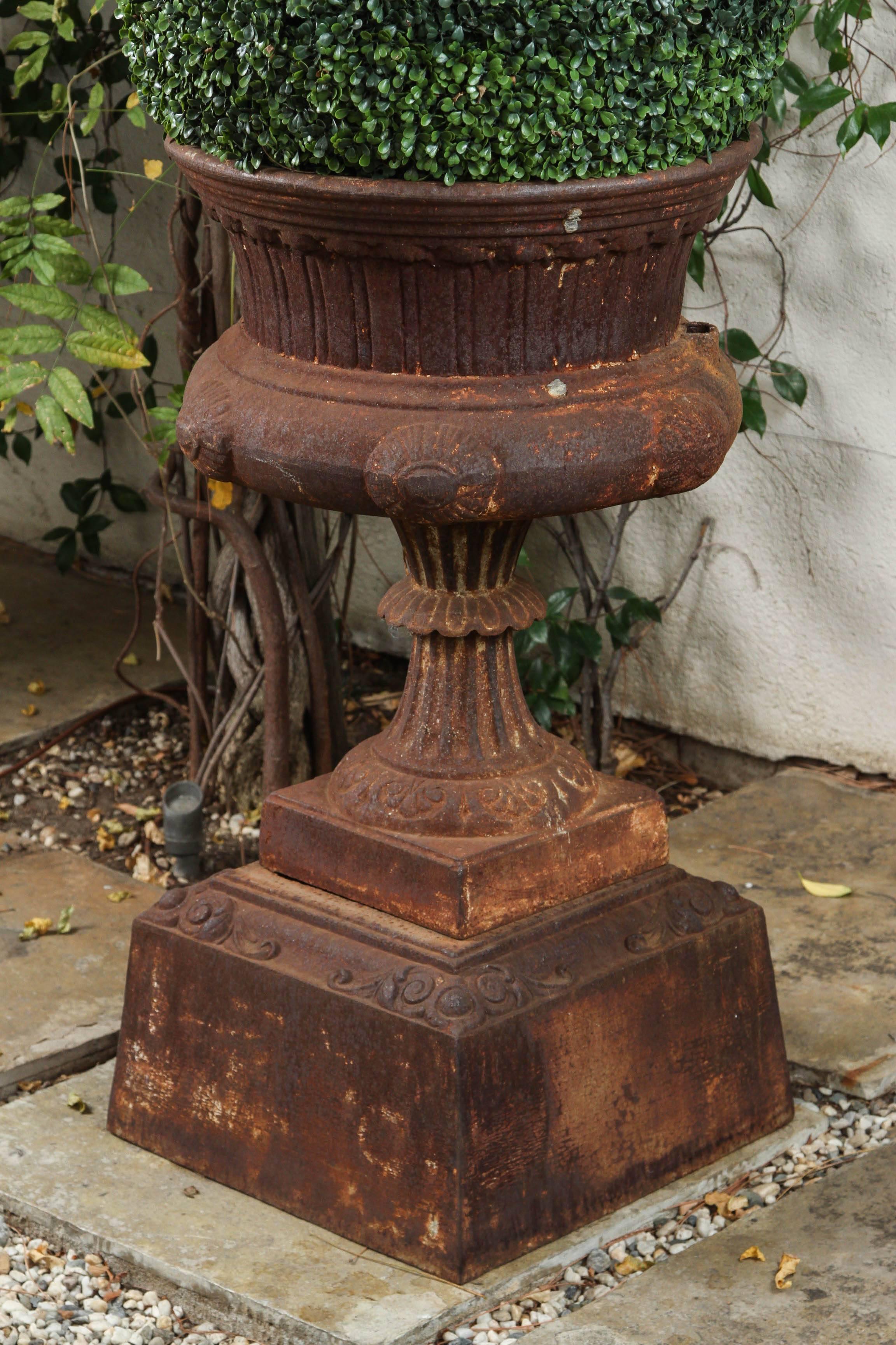 A large late 19th century American cast iron garden urn on a plinth base.