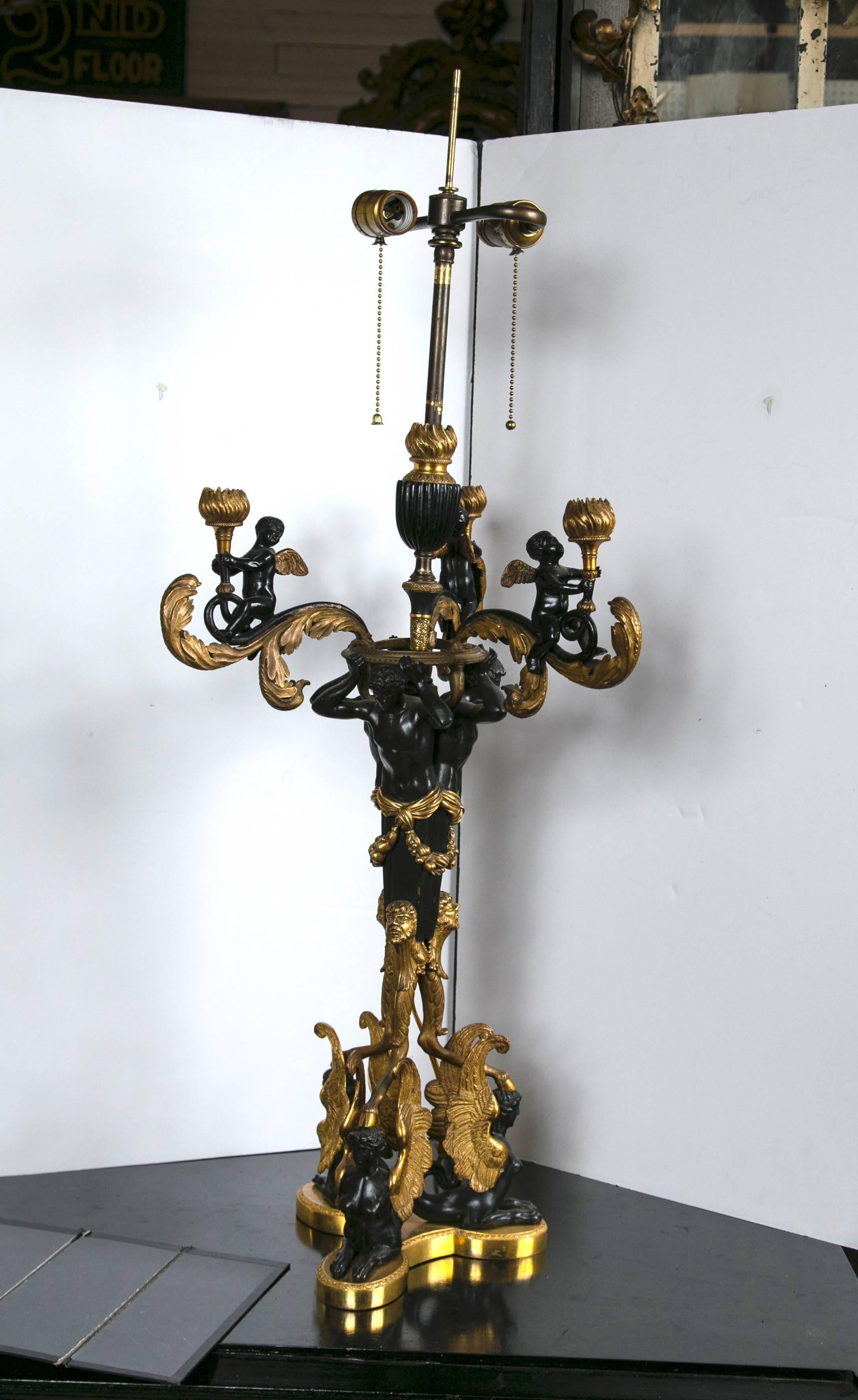 An outstanding pair of gilt and patinated bronze candelabra with triple lobed base upon which sits three female, winged, fish tailed figures. Attached to their heads are cloven hoofs at the end of long legs rising up to three bearded male