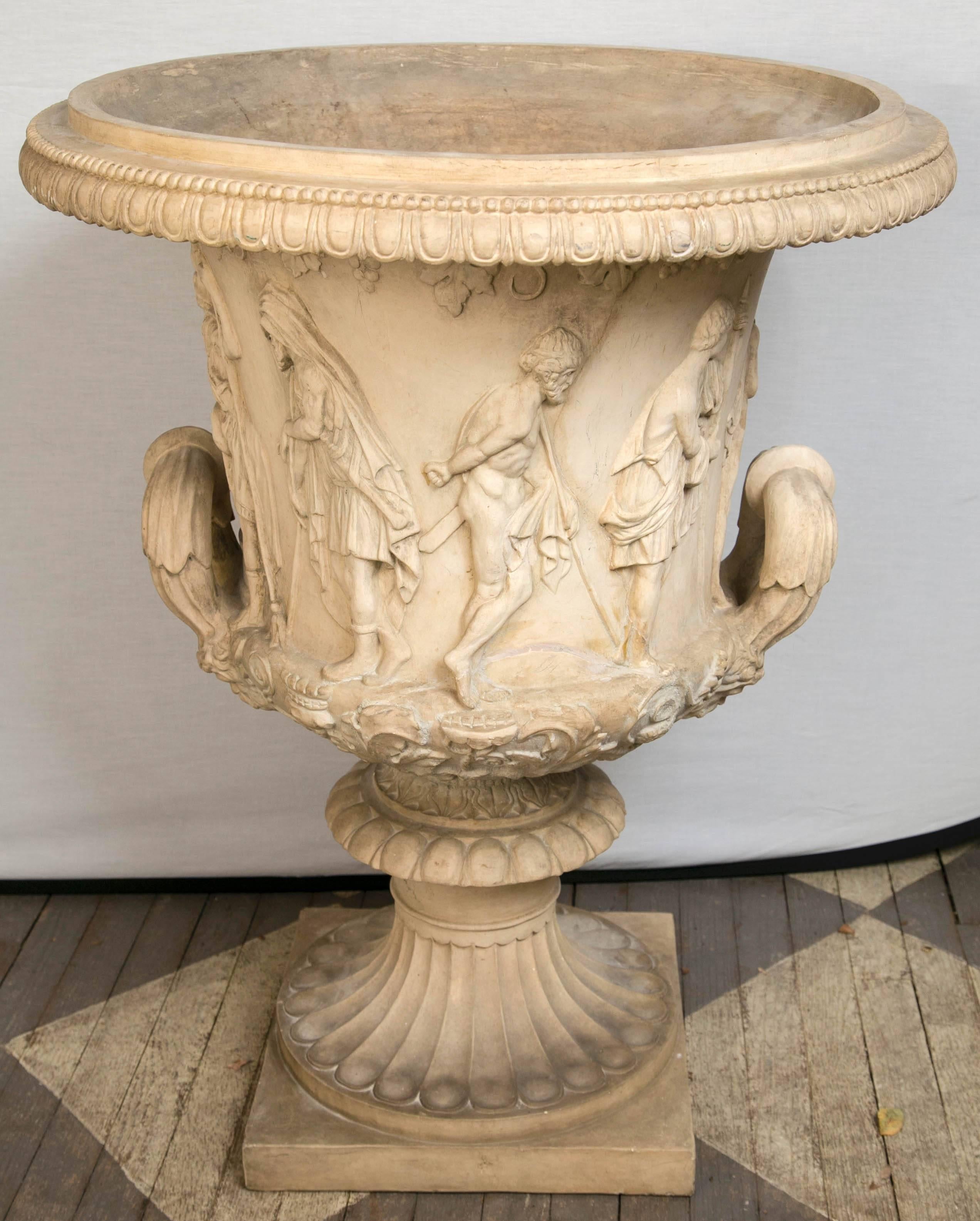 Impressive size Italian white terracotta neoclassic urn with a gadrooned and beaded rim. Below the rim are grapes, grape leaves the vines. The body decorated with ancient roman style figures and large handles. The socle is attached tom the body with
