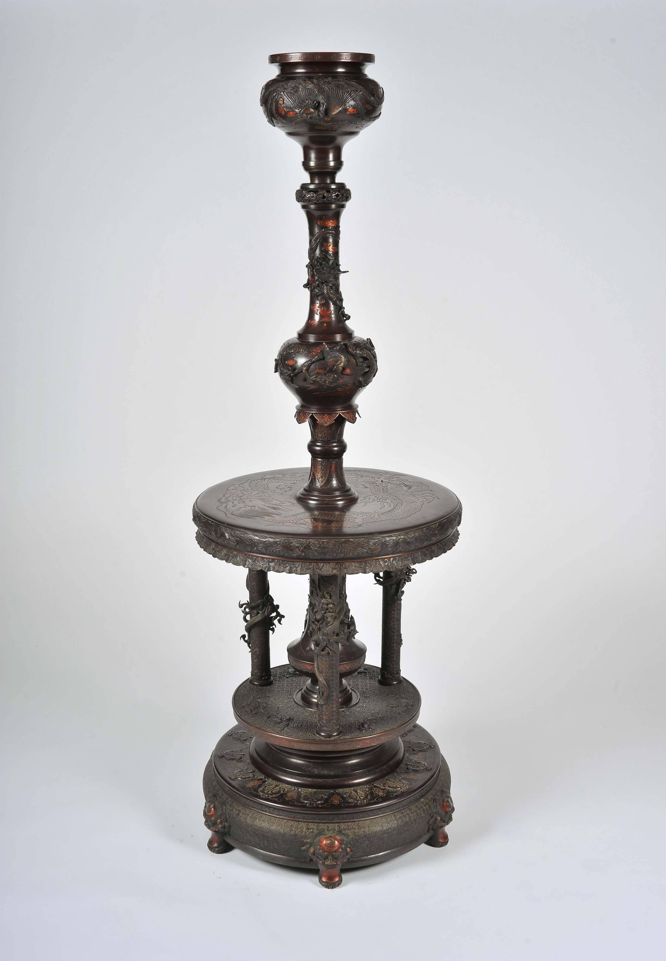 An early 20th century Japanese bronze stand with adjustable column. With profuse cast and chased decoration throughout this was most likely for burning incense.
The lower section with three supporting legs with entwined dragons, below a 