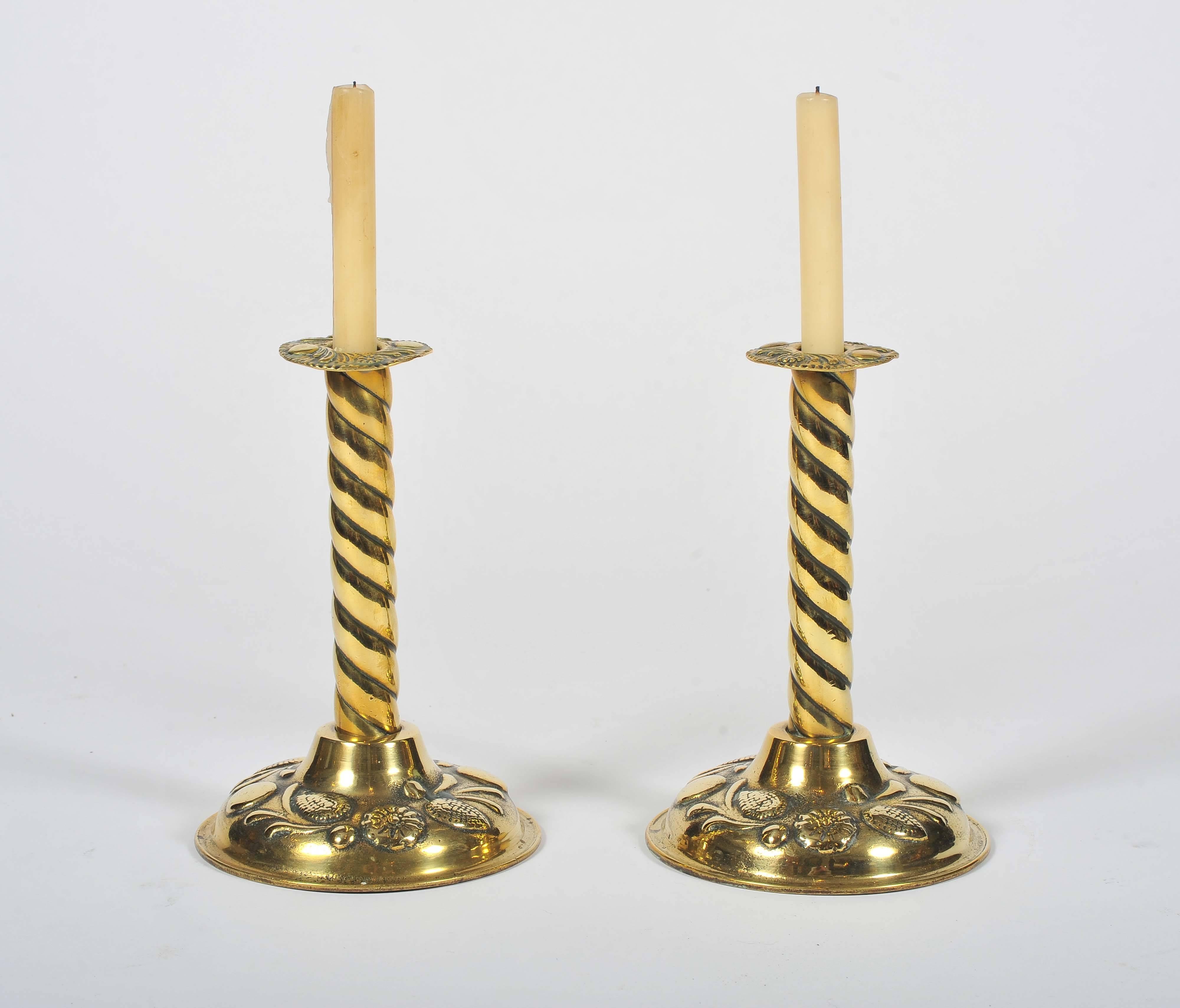 A most unusual pair of 19th century brass candlesticks. The stems of barley twist design, the pressed rims and cast bell shaped bases with fine foliate and floral decoration.
