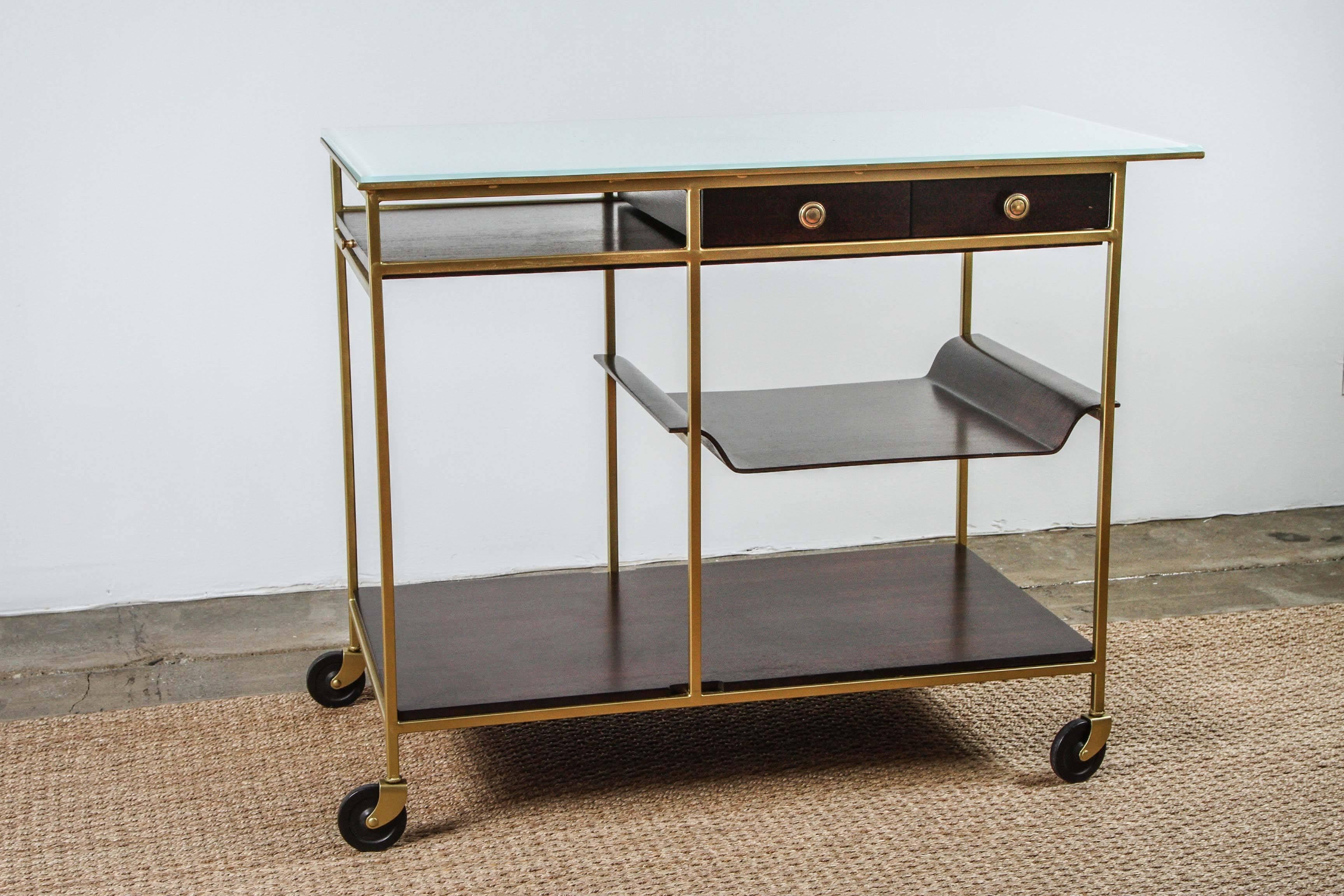 This rare Mid-Century Modern tea/bar cart was designed by Paul McCobb for the Irwin Collection by Calvin, Grand Rapids, USA, circa 1950s. It features a solid brass frame that rests on four casters; drawers and a removable tray; and a white milk