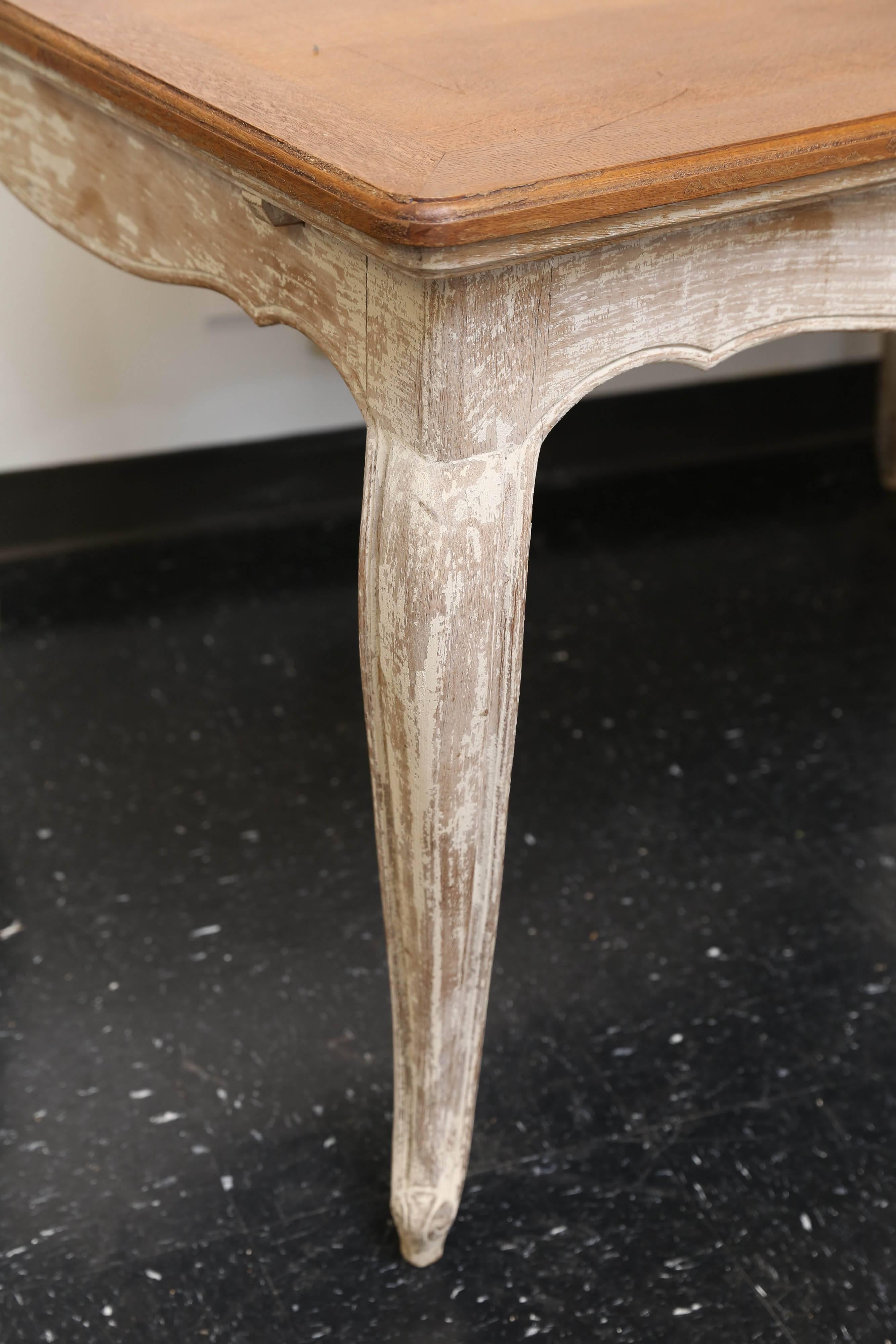 Early 20th century French table with a waxed top and a scraped paint base. There are two pull-out extensions under the top that are in scraped paint. Height to apron is 24