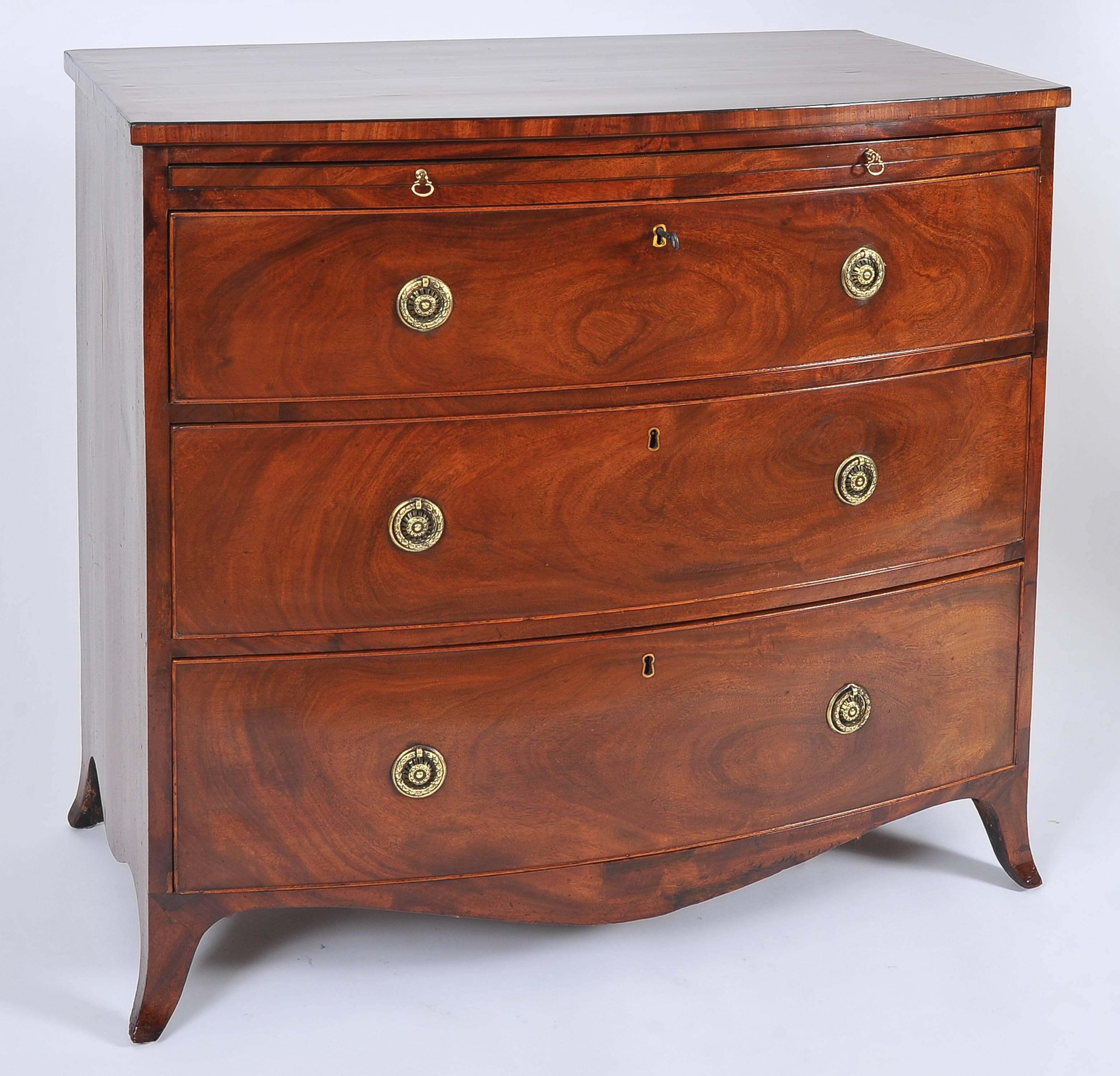 This striking and beautifully patinated Georgian bow fronted mahogany chest of drawers features three graduated drawers and baize lined brushing slide. The chest has brass pull rings and working locks for all the drawers with a key. There is ebony