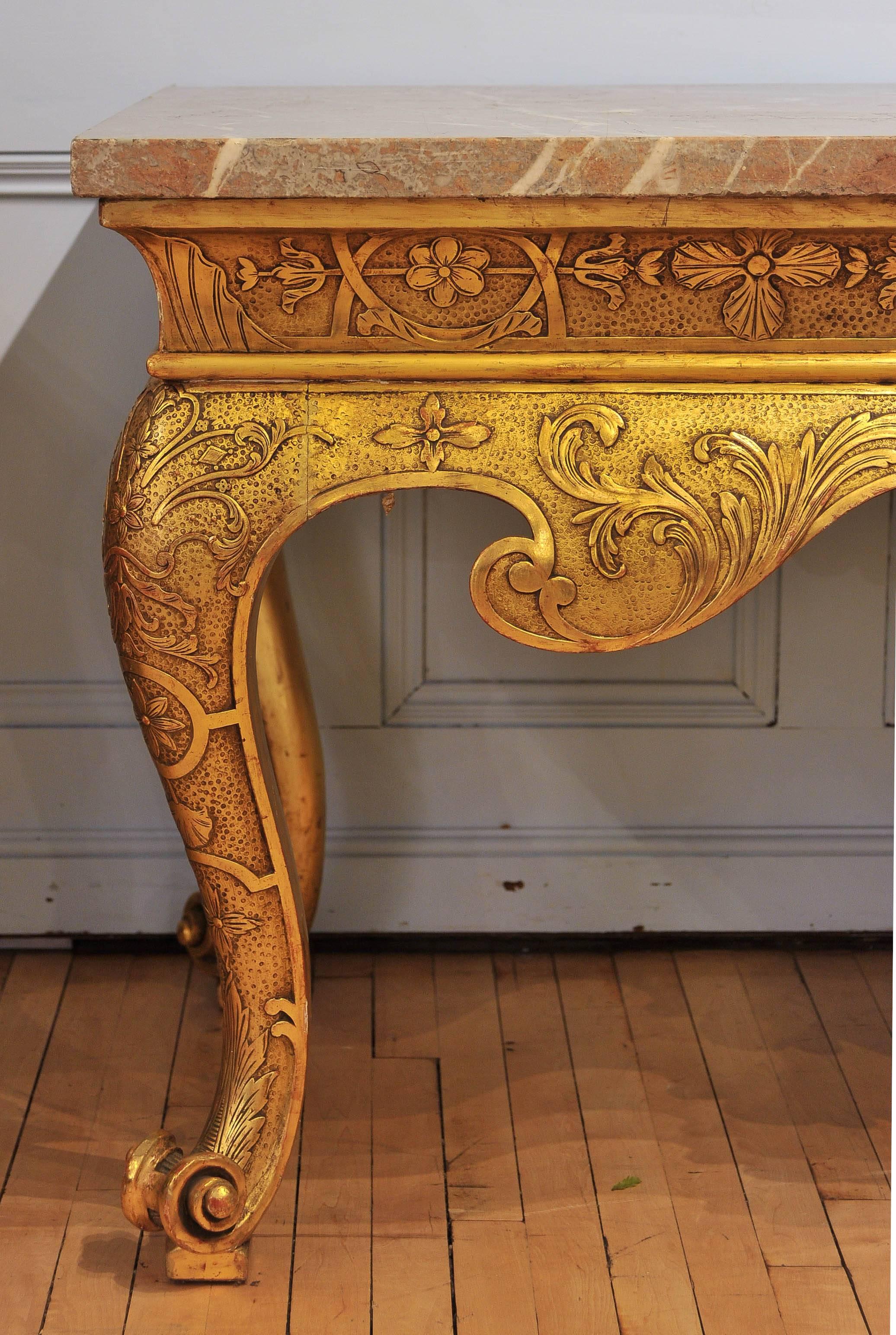 This magnificent and grandiose pair of 19th century gilt consoles feature substantial tops supported on bold and ornate cabriole legs with scroll feet. The marble measures 1 ½ in - 4 cm thick and the consoles have an all-over decorative floral and