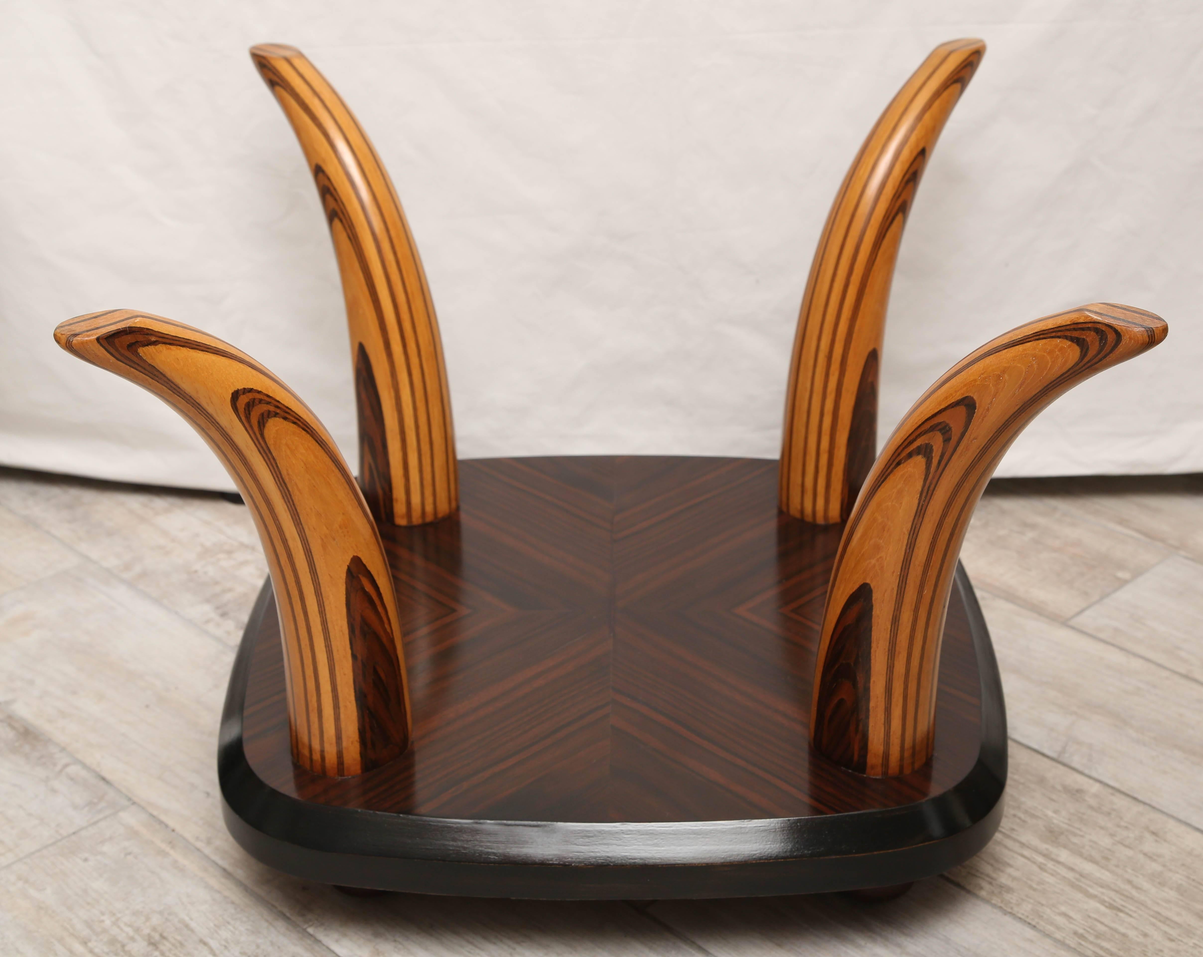 Striking tiger wood coffee table with beveled glass top supported by four wood horns.