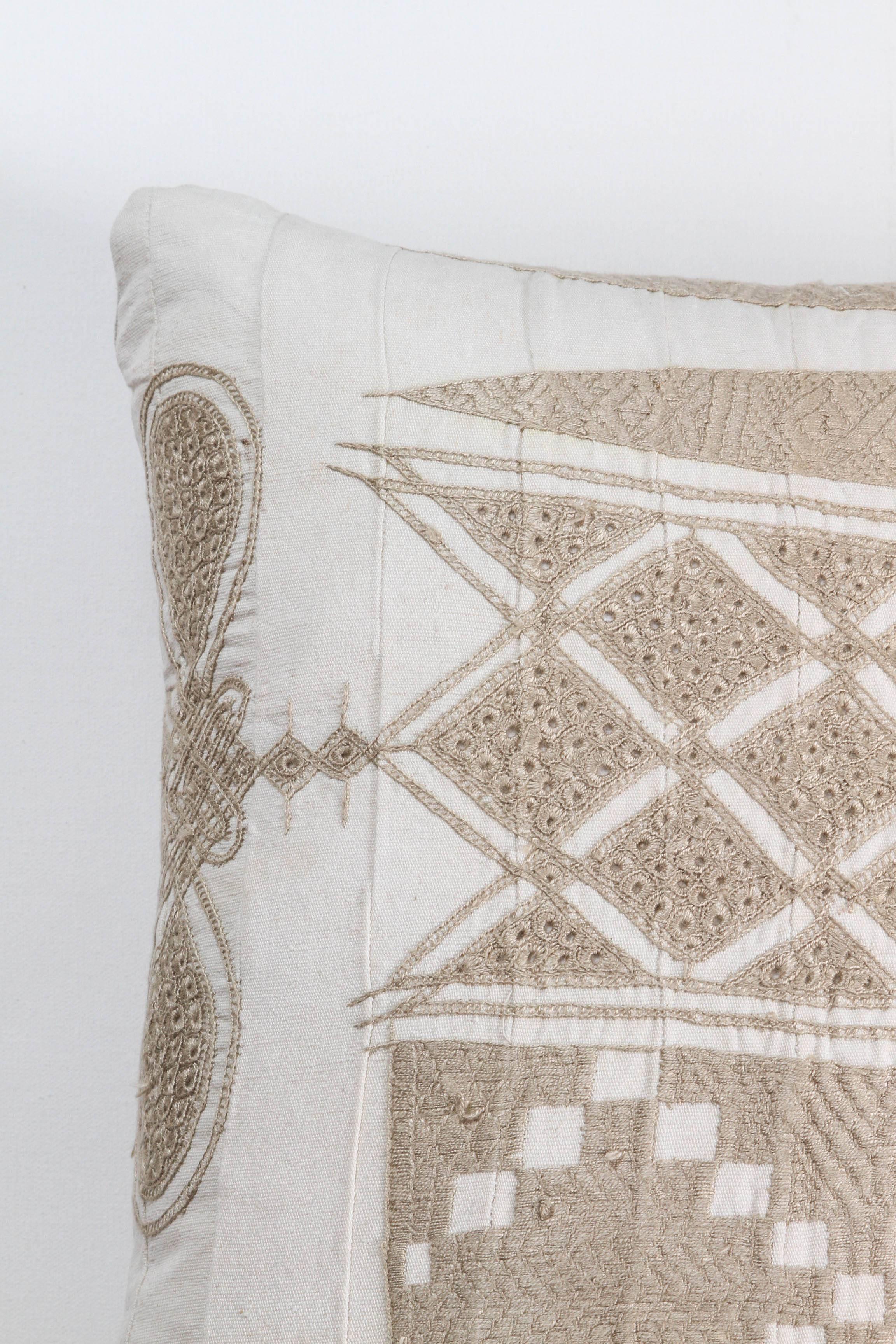 Cushion or pillow made from a Hausa Chief’s Robe, known as a Boubou. Hausa is the largest tribal group in Nigeria. Hand worked cotton floss embroidery over hand woven fabric made in narrow panels sewn together. Backed with natural linen, feather and