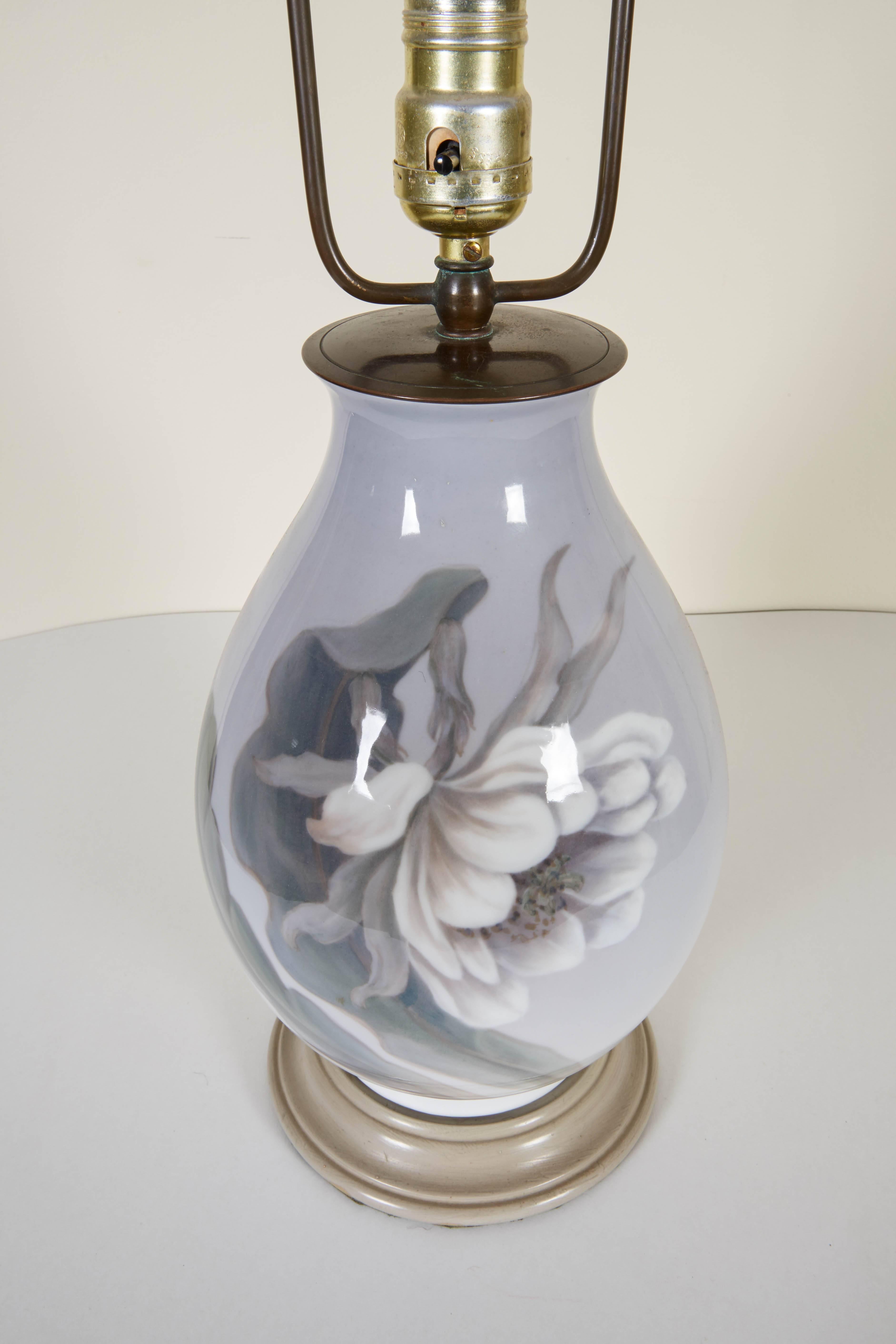 Vintage pair of lamps each decorated en grisaille with a large peony blossom and butterflies to the reverse; with turned painted wood base. Height to top of vase is 12.5