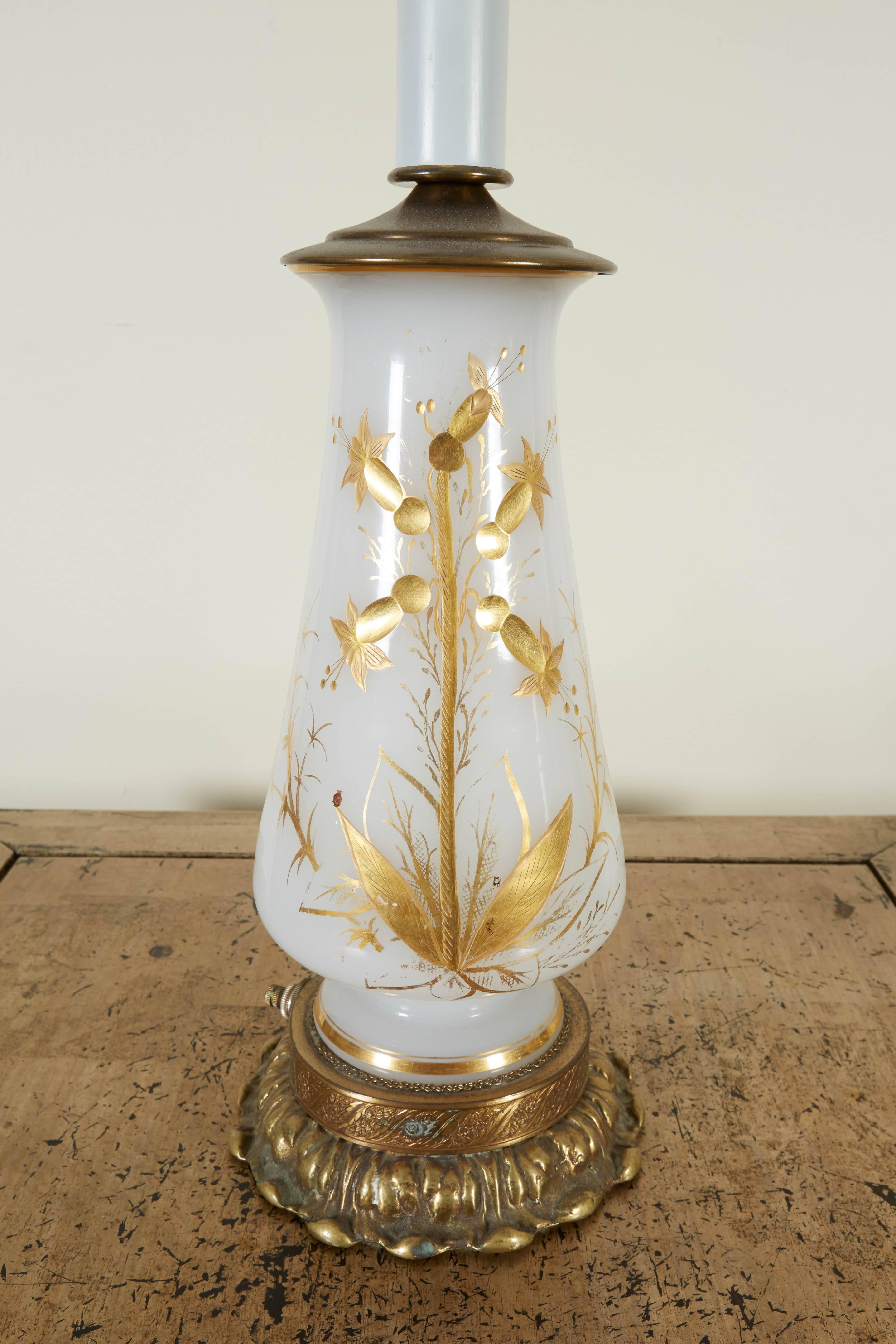 Each with vase hand-painted with a gilt floral spray mounted on a foliate gilt brass base. With removable harp surmounted by a flame finial. Height to top of vase is 12