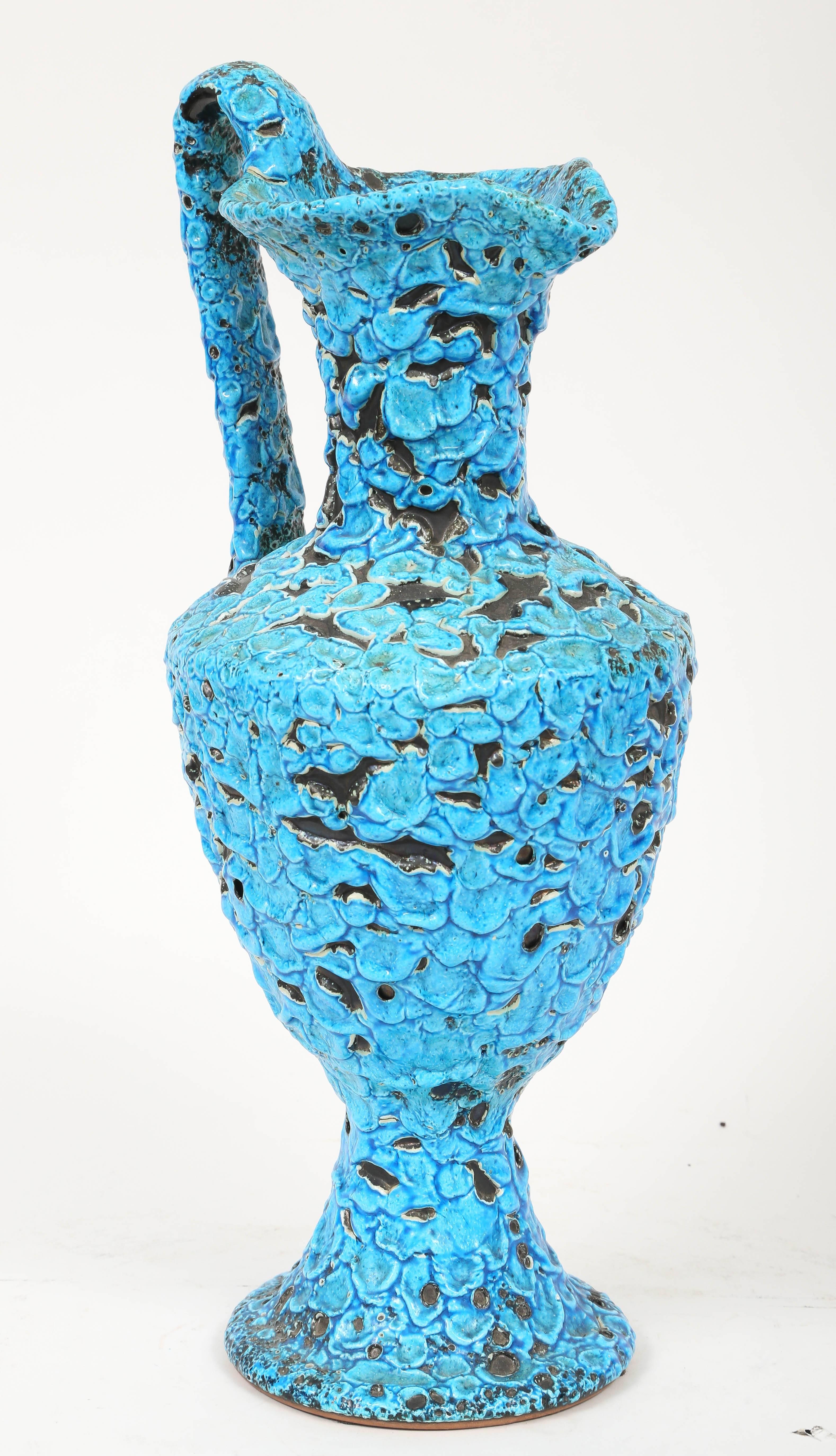 The distinctive glaze on this tall pitcher vase was developed by Charles Cart the founder of the Le Cyclope Pottery brand in Annecy-le-Vieux in the Haute Savoie area of France. The firing process reveals the black layer below the turquoise glaze in