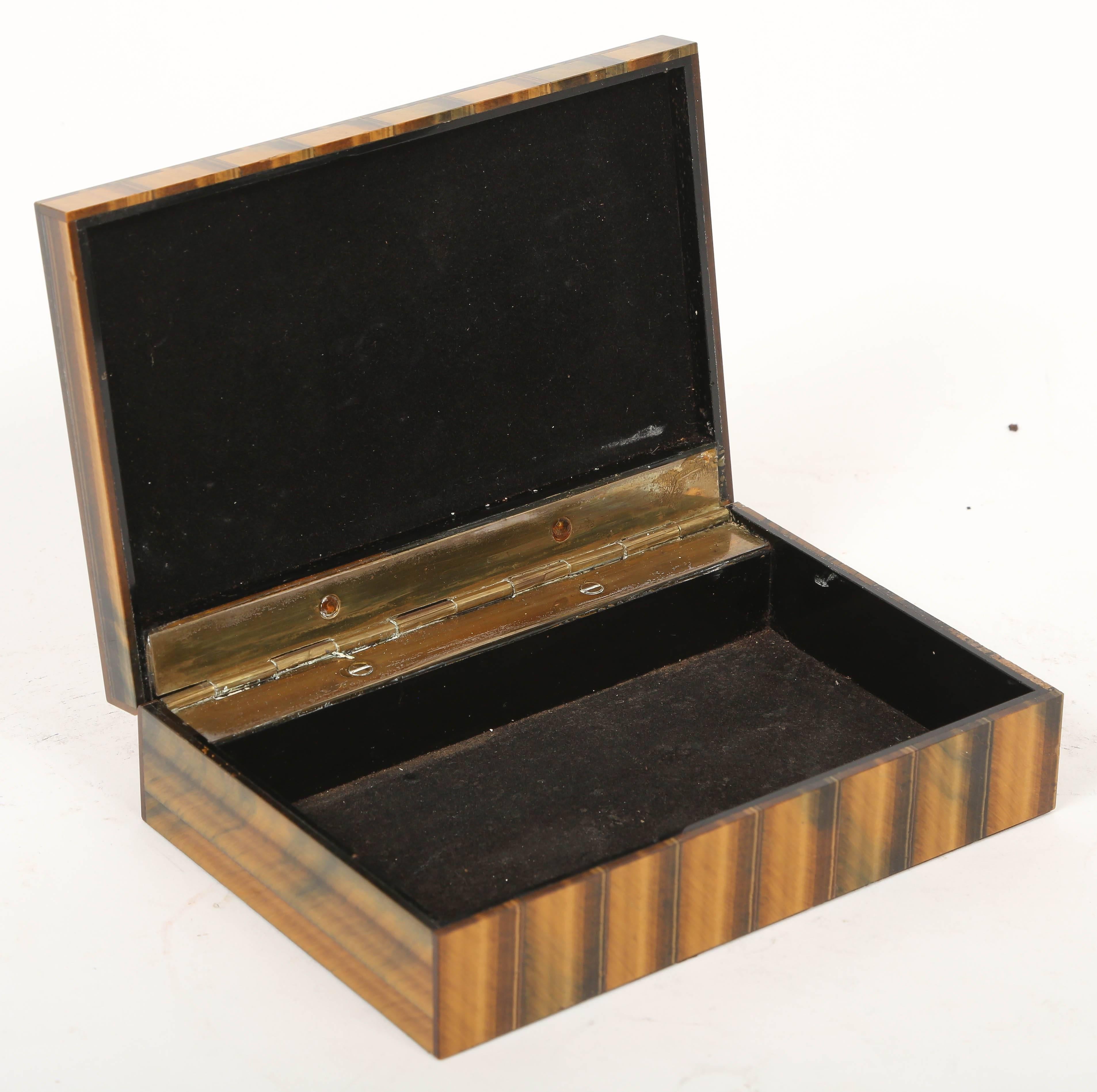 Brass hinged box with black velvet interior. A refined tabletop object of exquisite craftsmanship. 

Tiger's eye is a chatoyant gemstone which is a member of the quartz family. It is highly prized for its contrasting bands of color and the depth