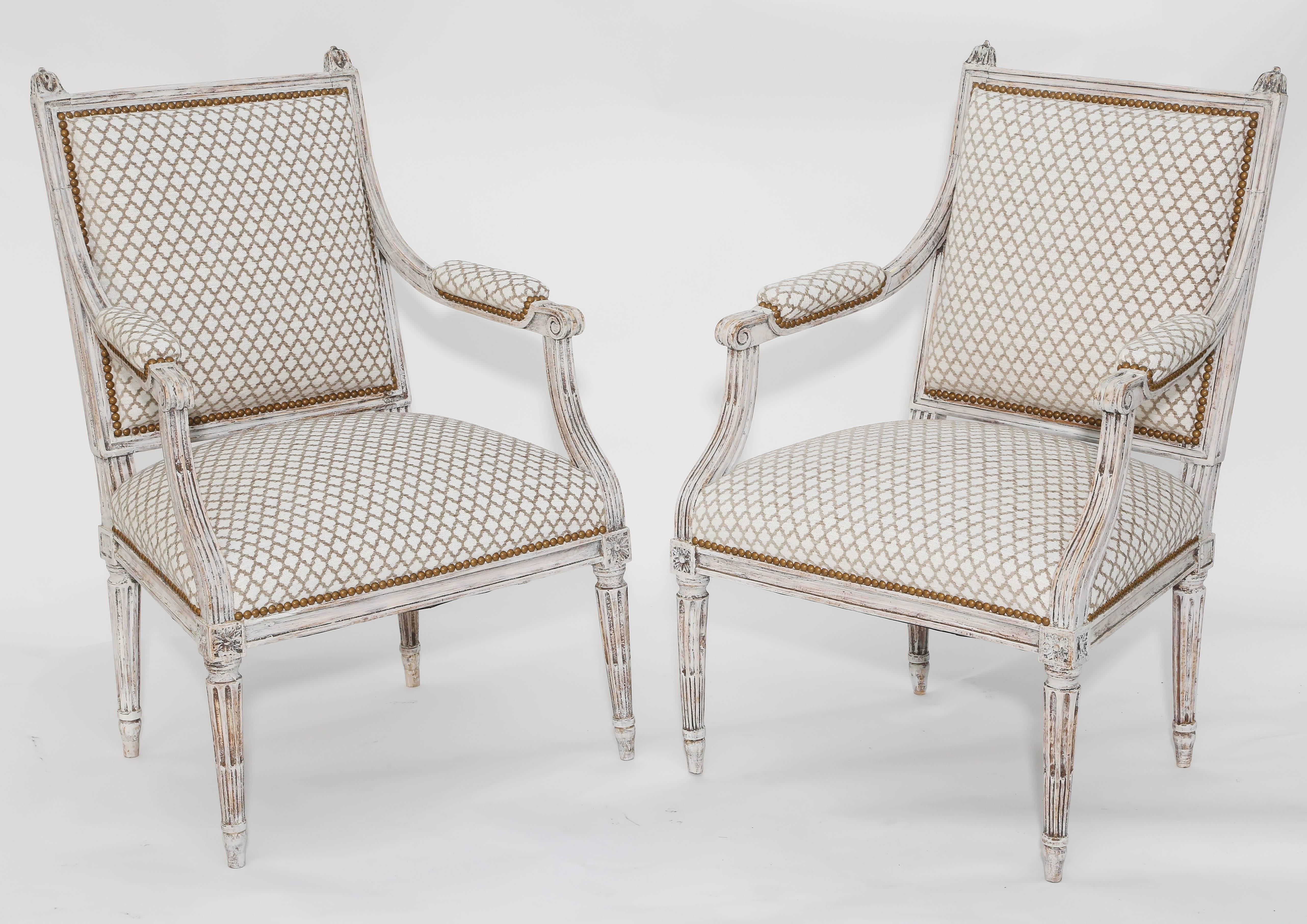 Pair of armchairs, having distressed painted finish, each with square back, outswept arms with padded elbow rests, back and crown seat with nailheads, raised on round fluted legs with toupie feet.

Stock ID: D9350