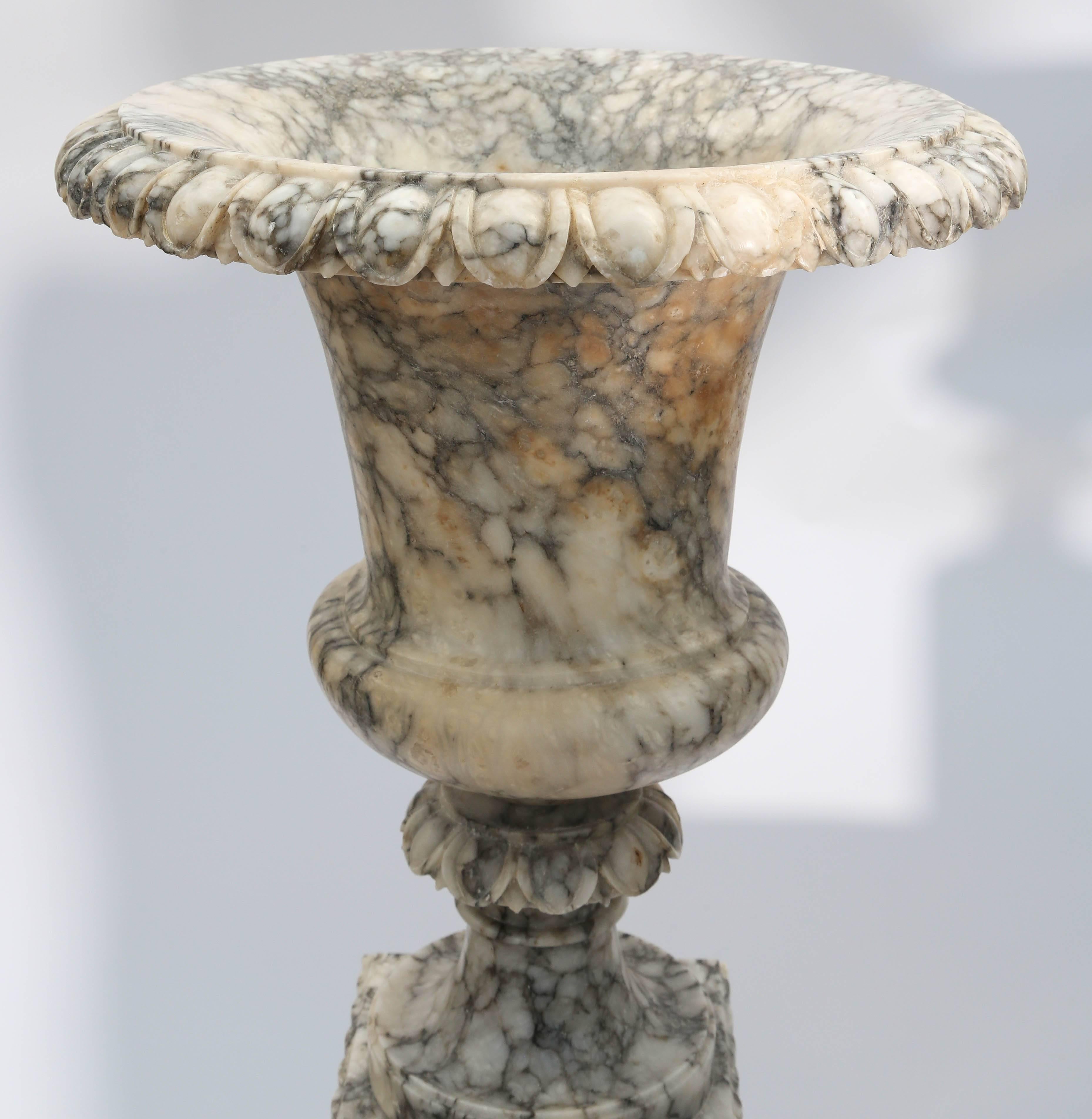 Pair of campana form urns on stands, of alabaster, both with egg-and-dart decorated rims and socles, on round foot, set upon graduating, fluted, square plinths.

Stock ID: D1914