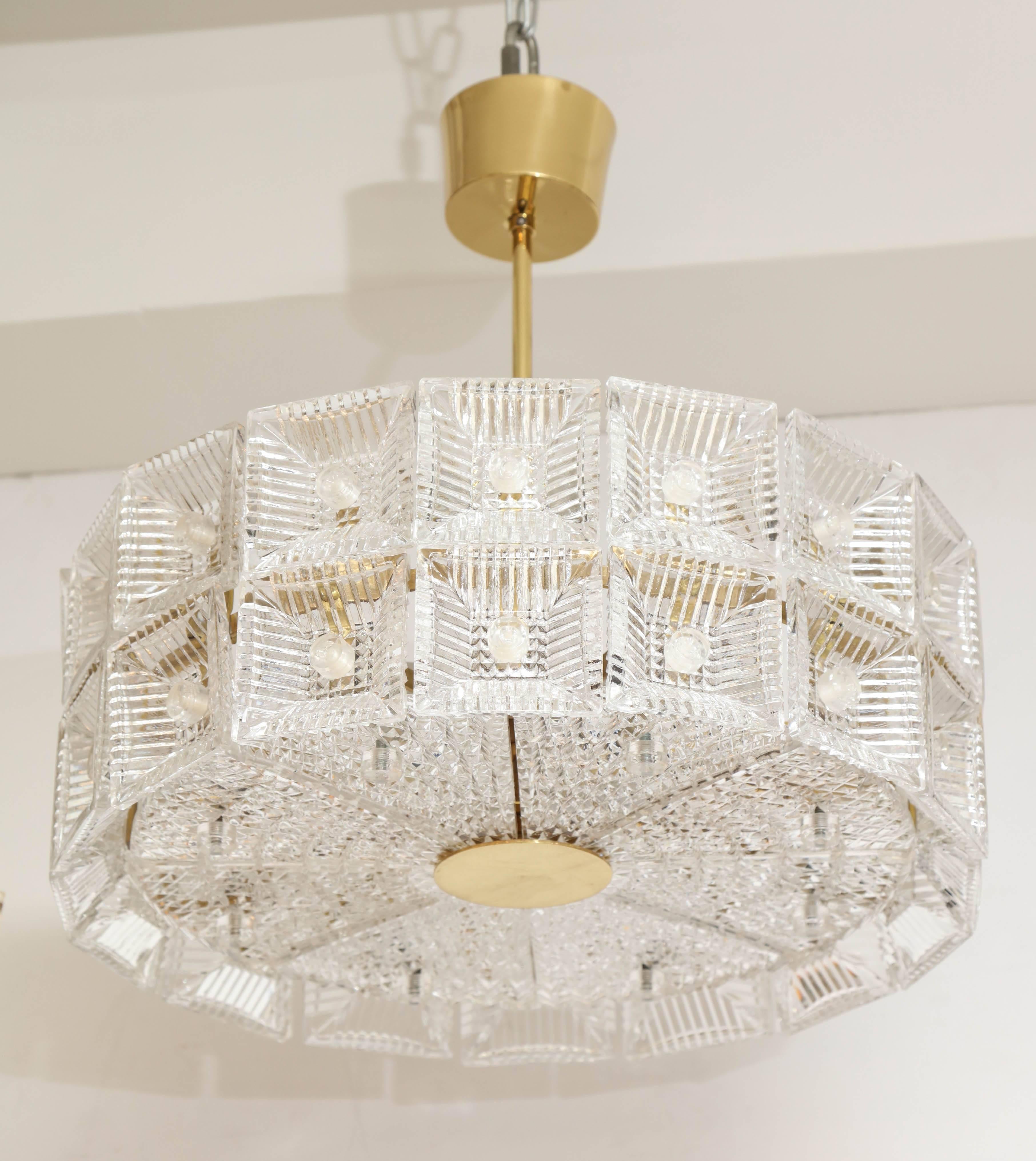 Large-scale Orrefors chandelier composed of two rows of square crystal elements and eight pie shaped pieces around the bottom all suspended on a brass frame stem and canopy. Rewired for use in the USA.