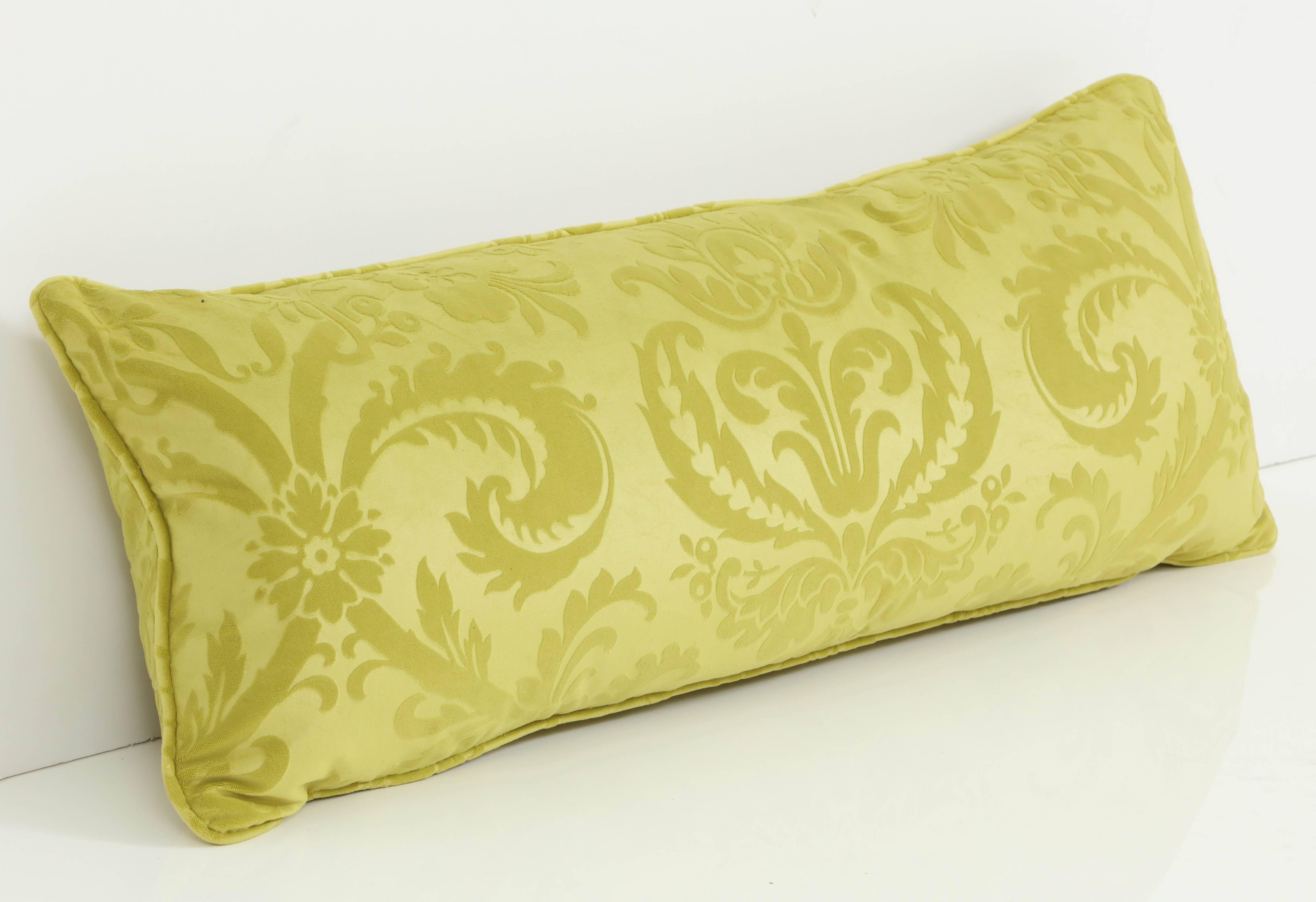 The acid green of this long cushion gives this traditional fabric a fresh, modern look. Perfect for a bed or on a sofa, the pillow's cut damask fabric is Pierre Frey.
