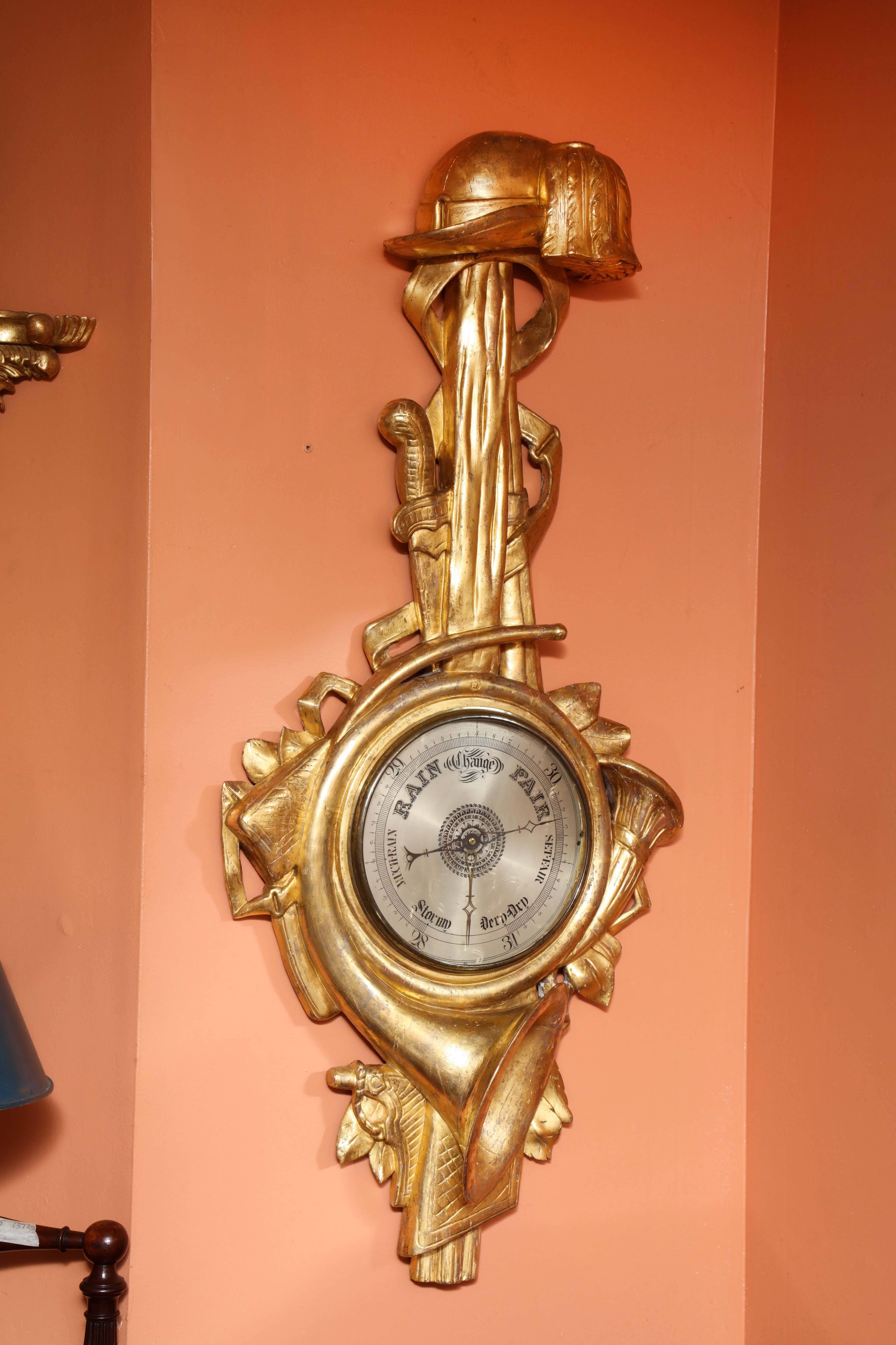 An unusual and fine French carved giltwood barometer with military theme of carved instruments ad weaponry.
