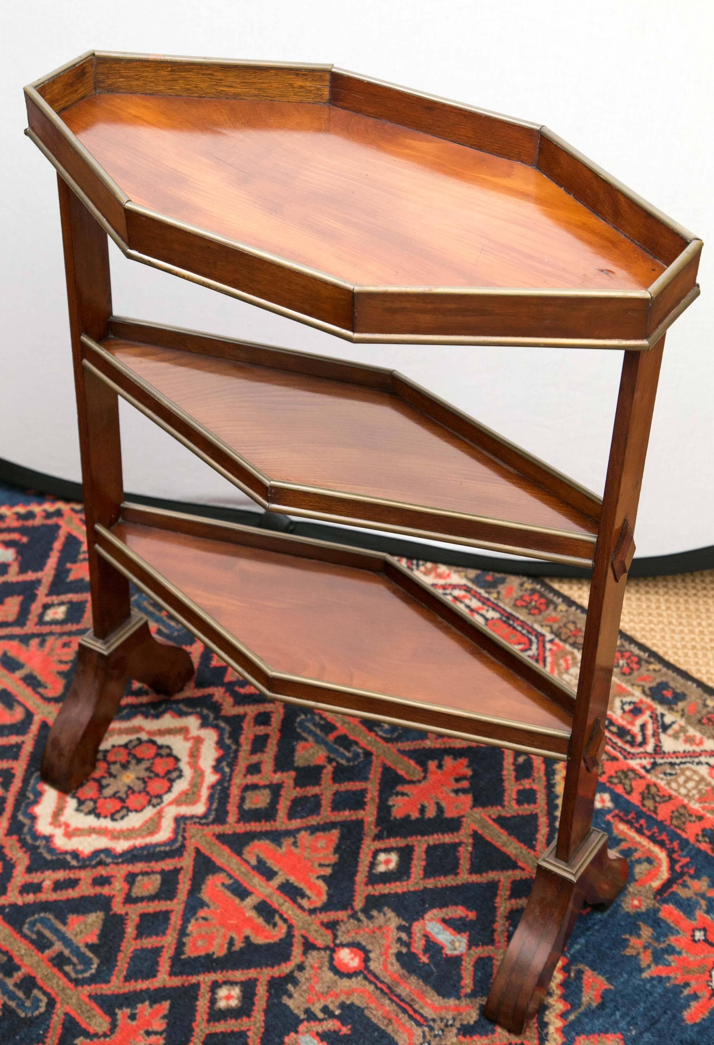 A diamond form mahogany three-tier table with a octagonal gallery top on trestle side supports.