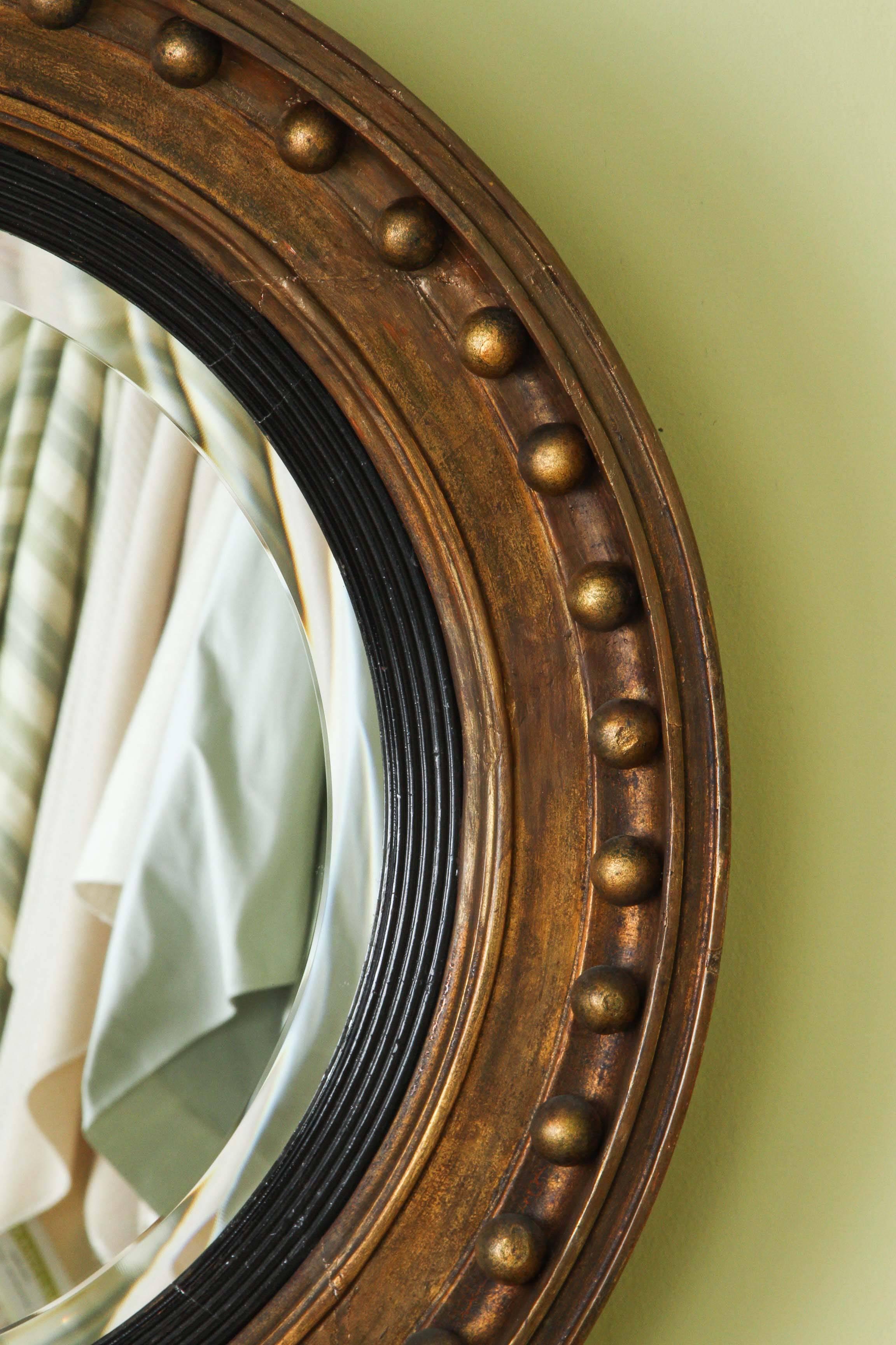 An English Regency round mirror, circa 1830, with a later, slightly convex beveled plate.