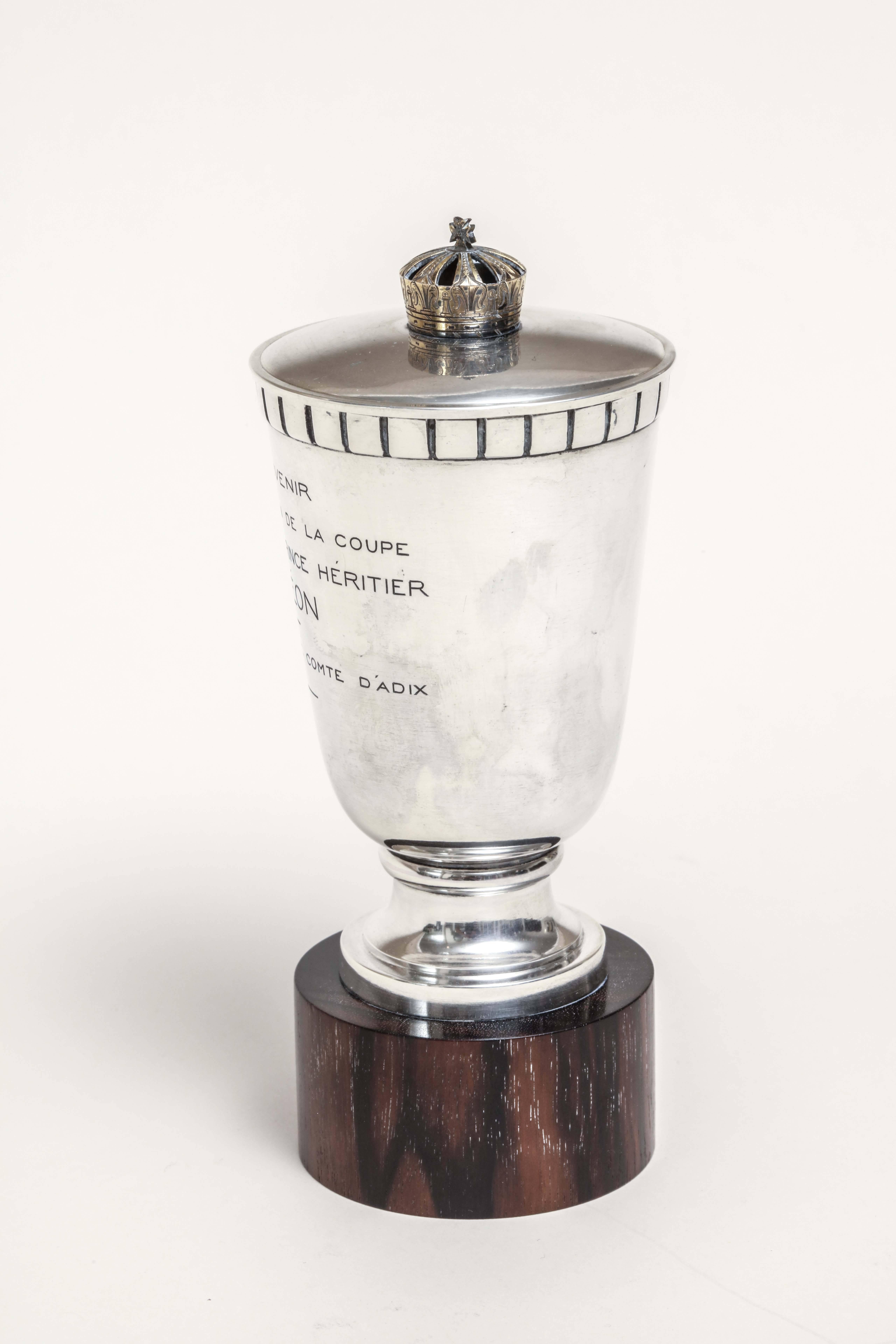 Sterling silver trophy mounted on ebony base with silver top and gilded finial. Has some engraving, including Prince Heritier Simeon.
Impressed with Minerve for 950 silver/ Jacque and Pierre Cardeilhac poincon/ Cardeilhac Paris.

Measures: 5 7/8”