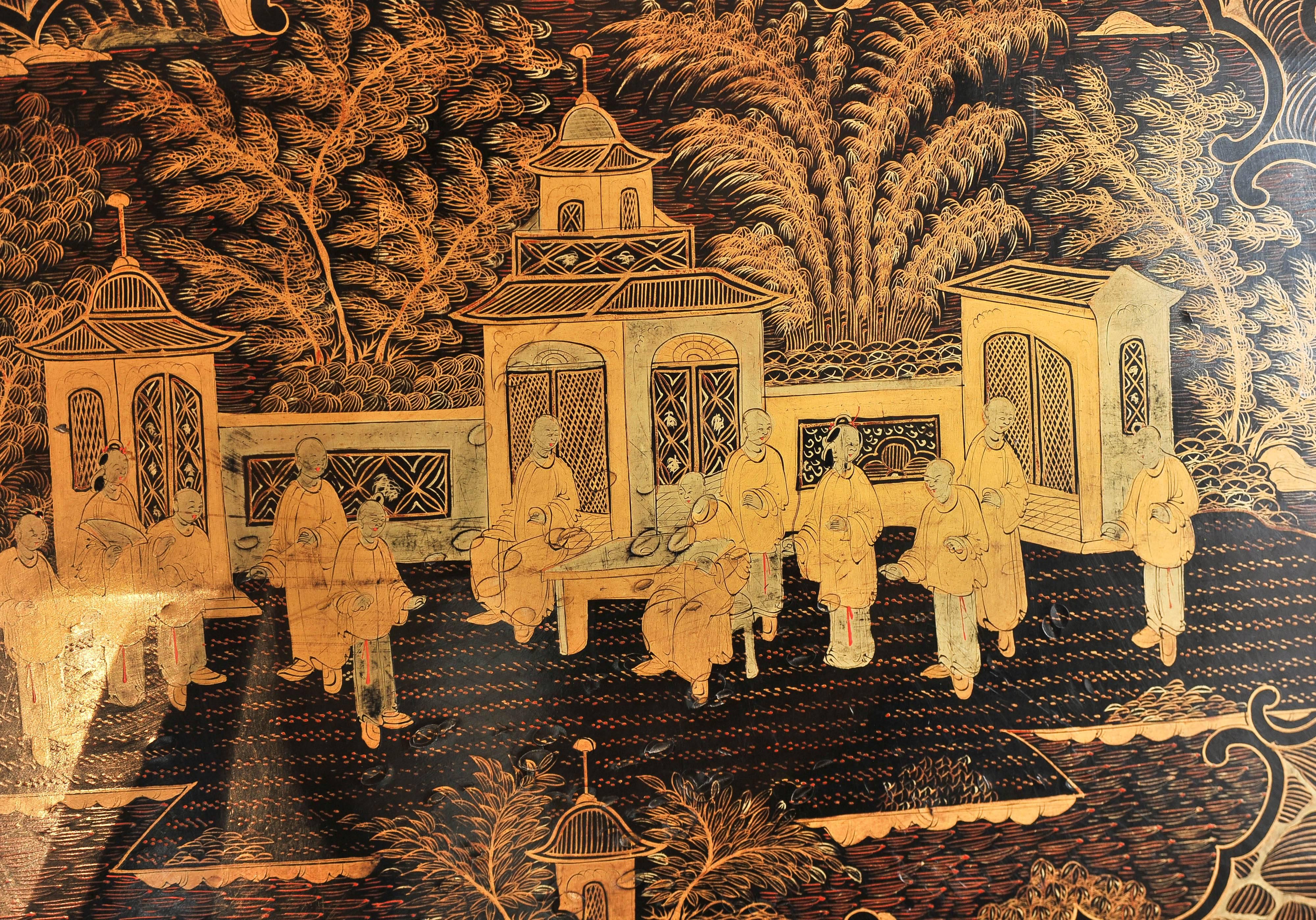 A highly decorative and finely painted Chinese lacquer tray decorated in gold on a black background depicting a large panel with courtiers among an architectural landscape with trees and a foliate border.
The tray has been repaired on the far right