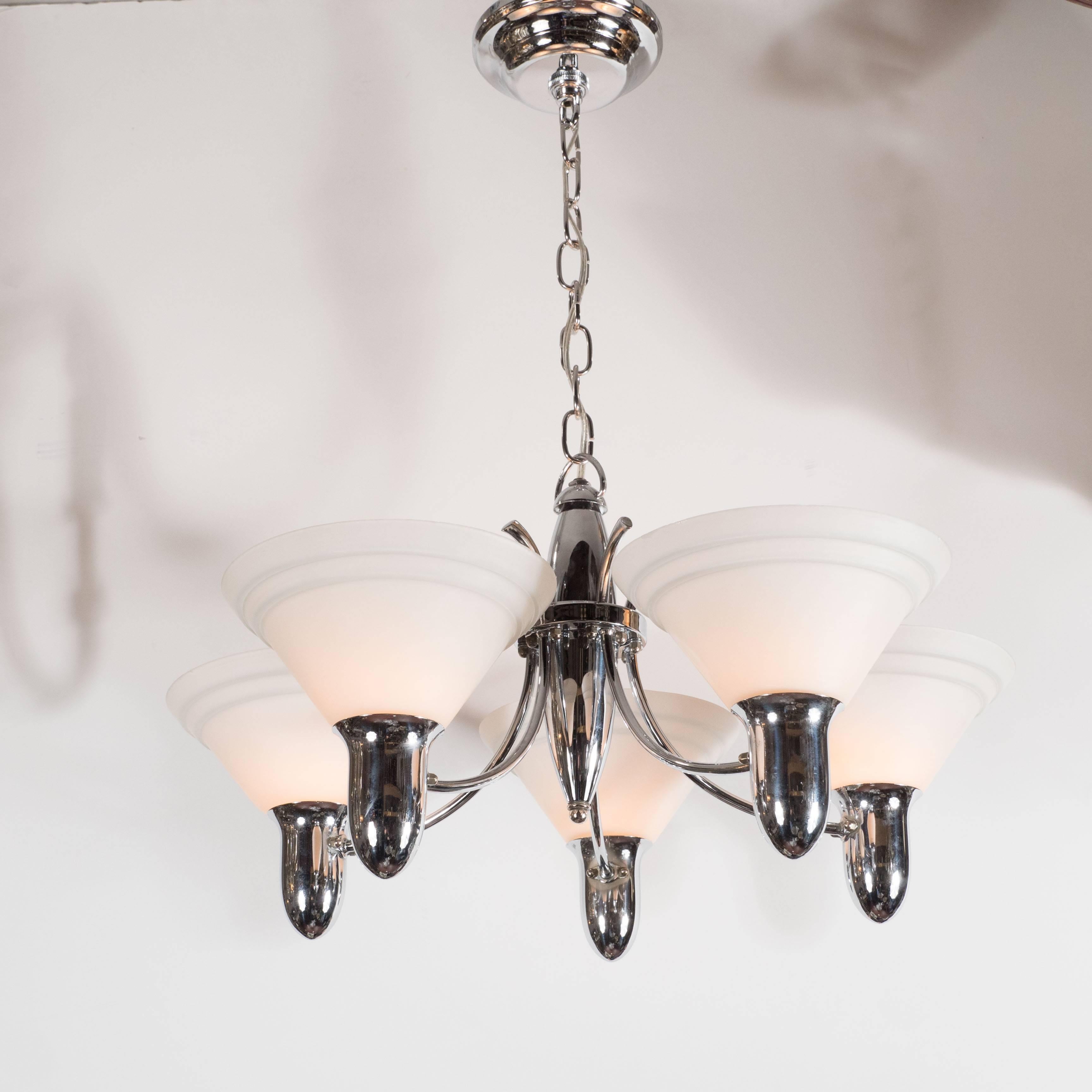 This wonderful chandelier is made of polished chrome and fitted with five uplight with hand blown crème glass shades with lineal detailing in grey. A great example of The Machine Ages influence on Art Deco in America. This piece has been completely
