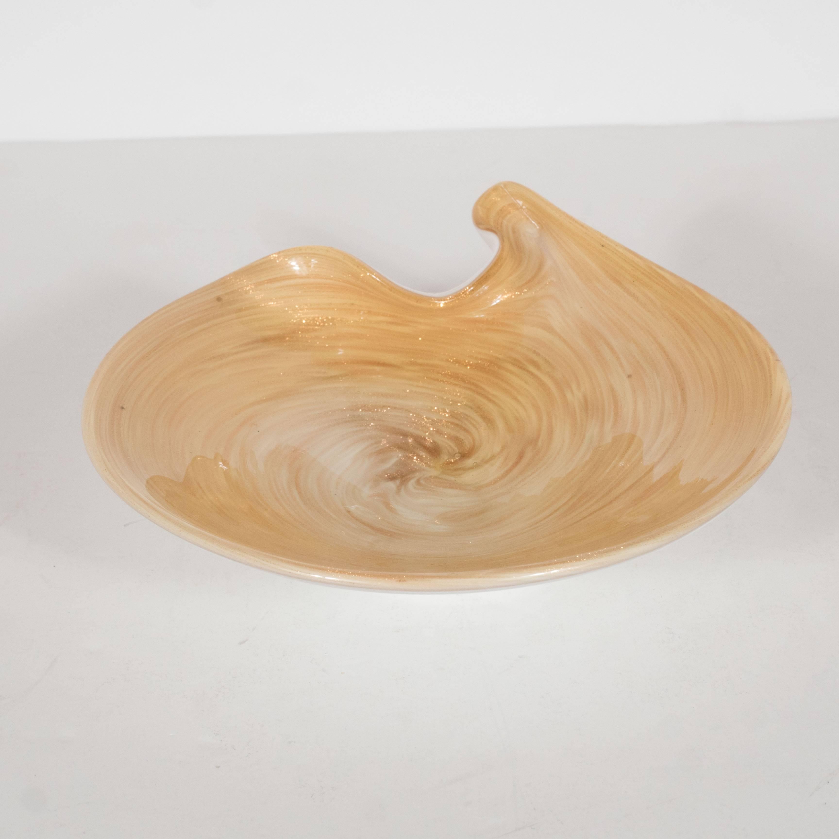 A Mid-Century Modernist handblown Murano glass dish or bowl in the form of a painter's color palette. This piece features a swirl of rich blends of 24-karat gold leaf in dust-form and cream, giving the piece warmth and movement. Its outside is