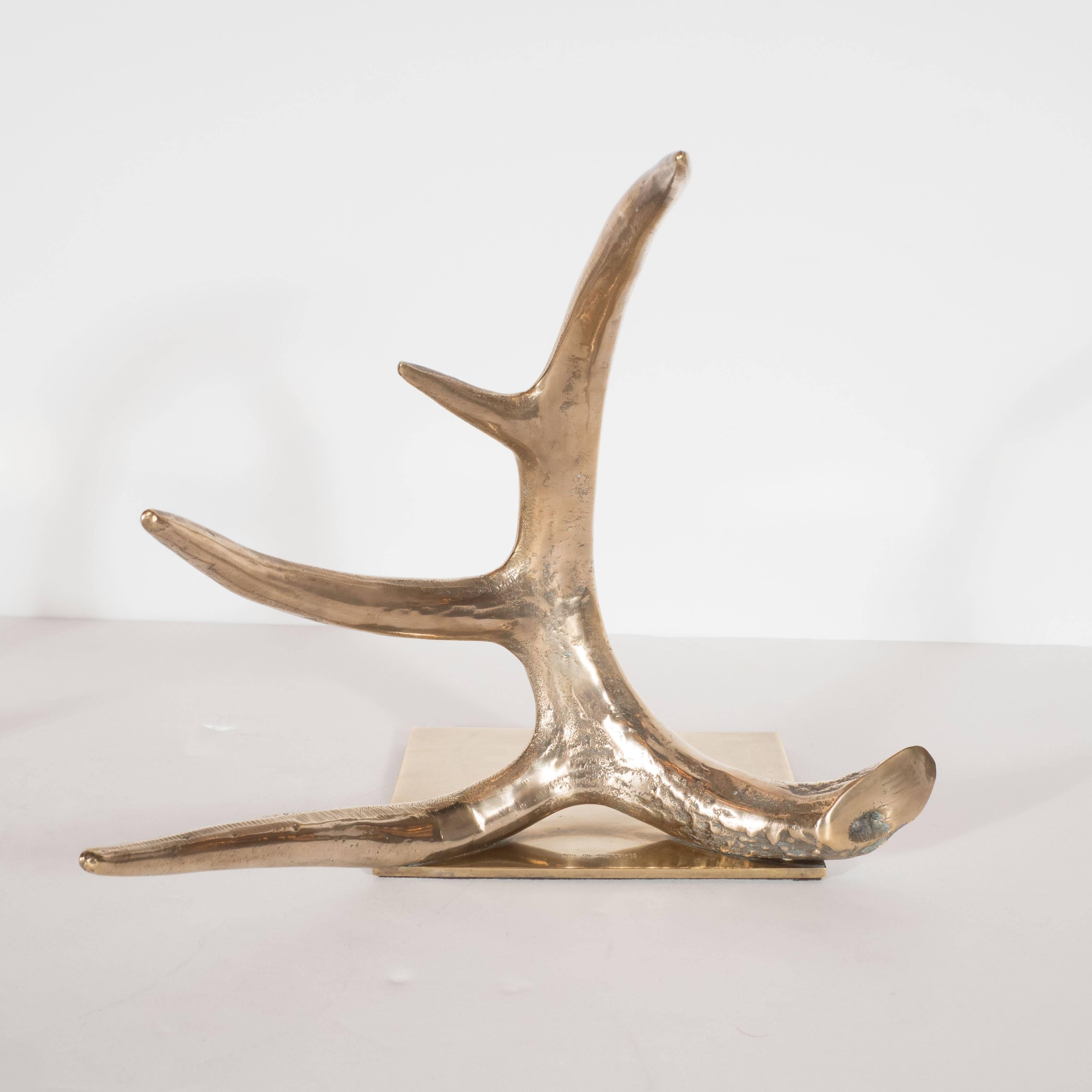 A chic pair of brass antler bookends by Arthur Court, 1978. Polished brass square base plates support mirrored brass antlers. Each features an intricately detailed burr, main beam and four points. The ideal pair to anchor a set of books on a