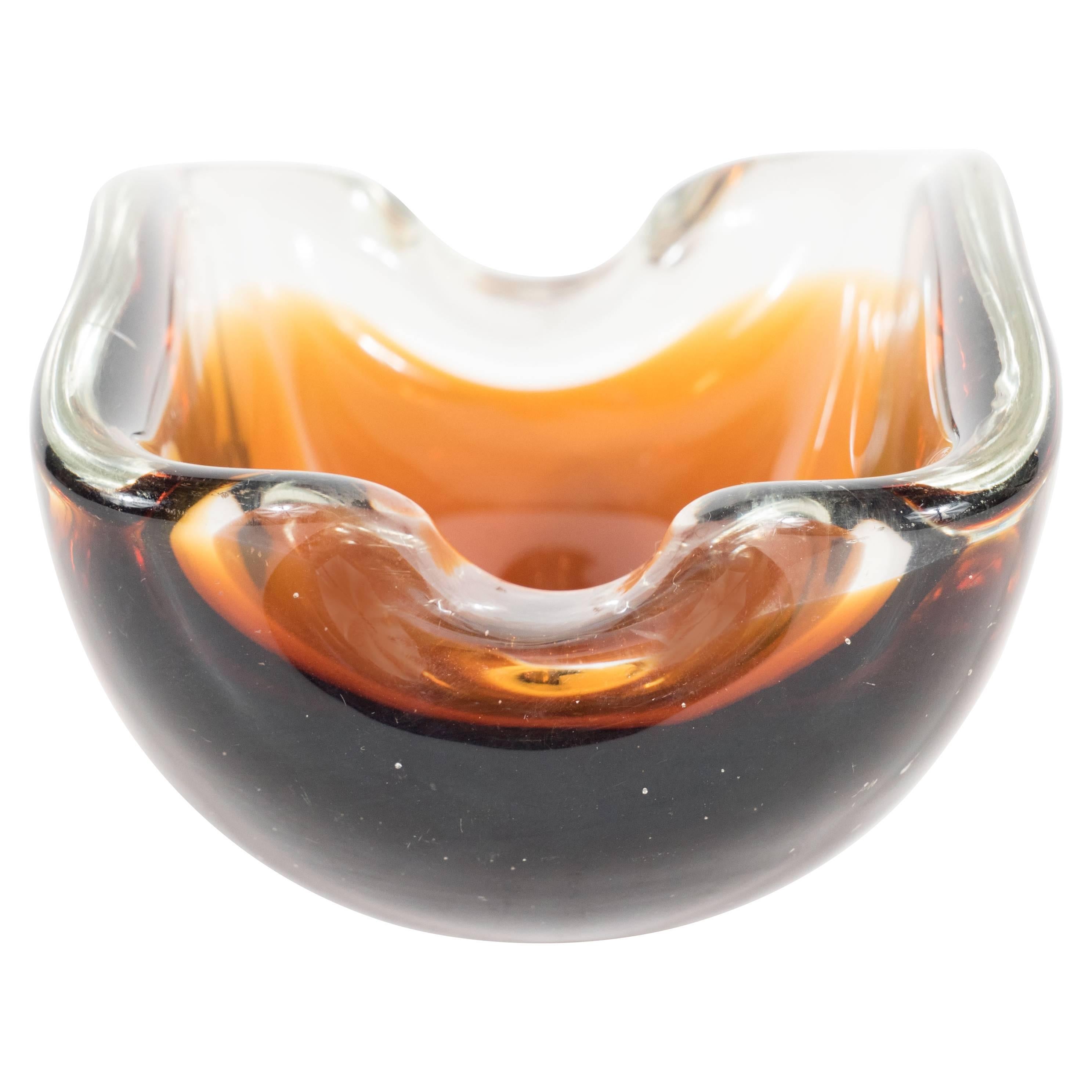 A Mid-Century Modernist handblown Murano ashtray in shades of smoky brown topaz. This piece consists of a disc form folded to create a cross-section form of a cylinder with two resting parts. This piece is in excellent condition.