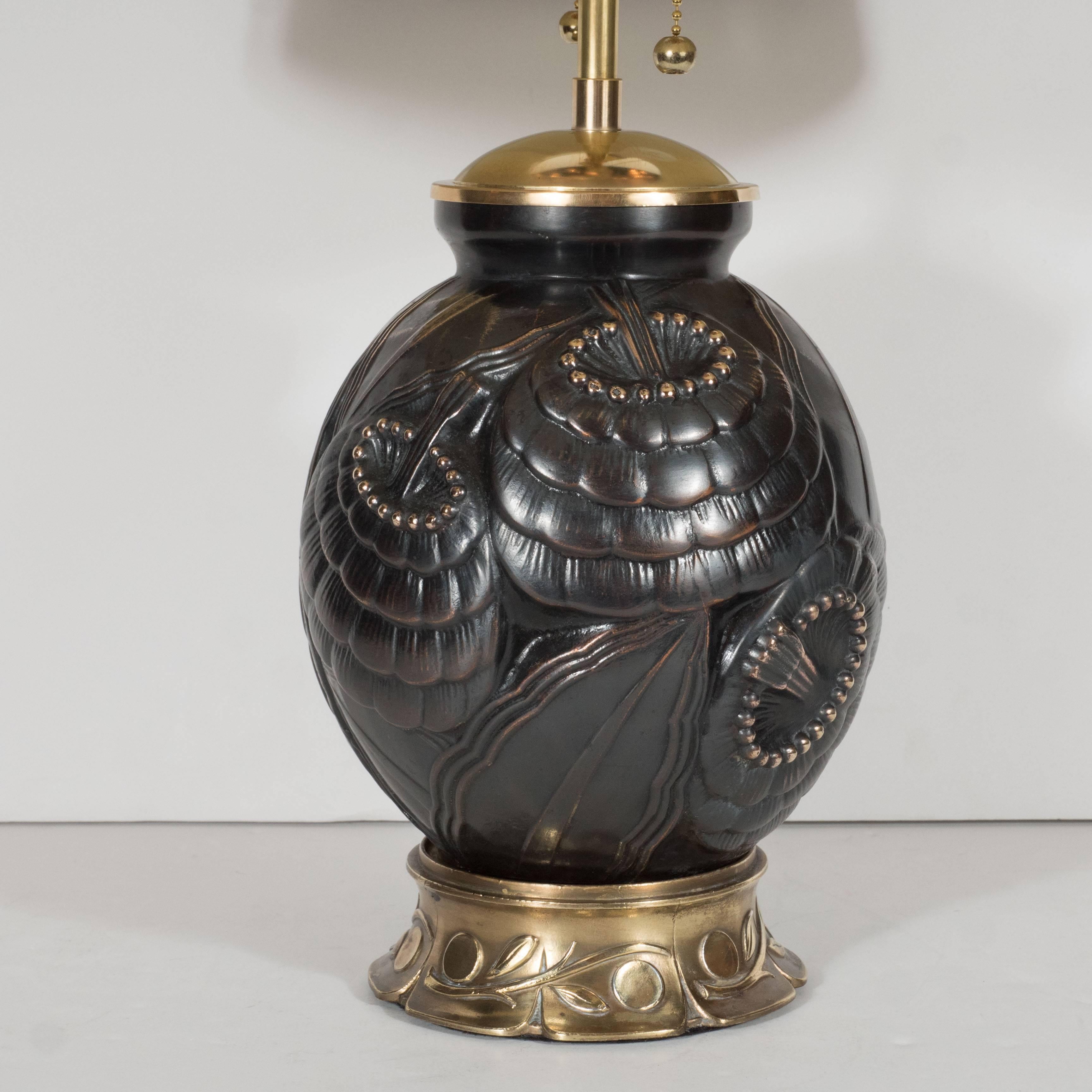 This exceptional lamp features a base and cap in antique brass and the body of the lamp is bronze with stylized floral and foliage detailing executed in an Art Deco Cubist manner in relief. The lamp has been completely rewired and is fitted with a