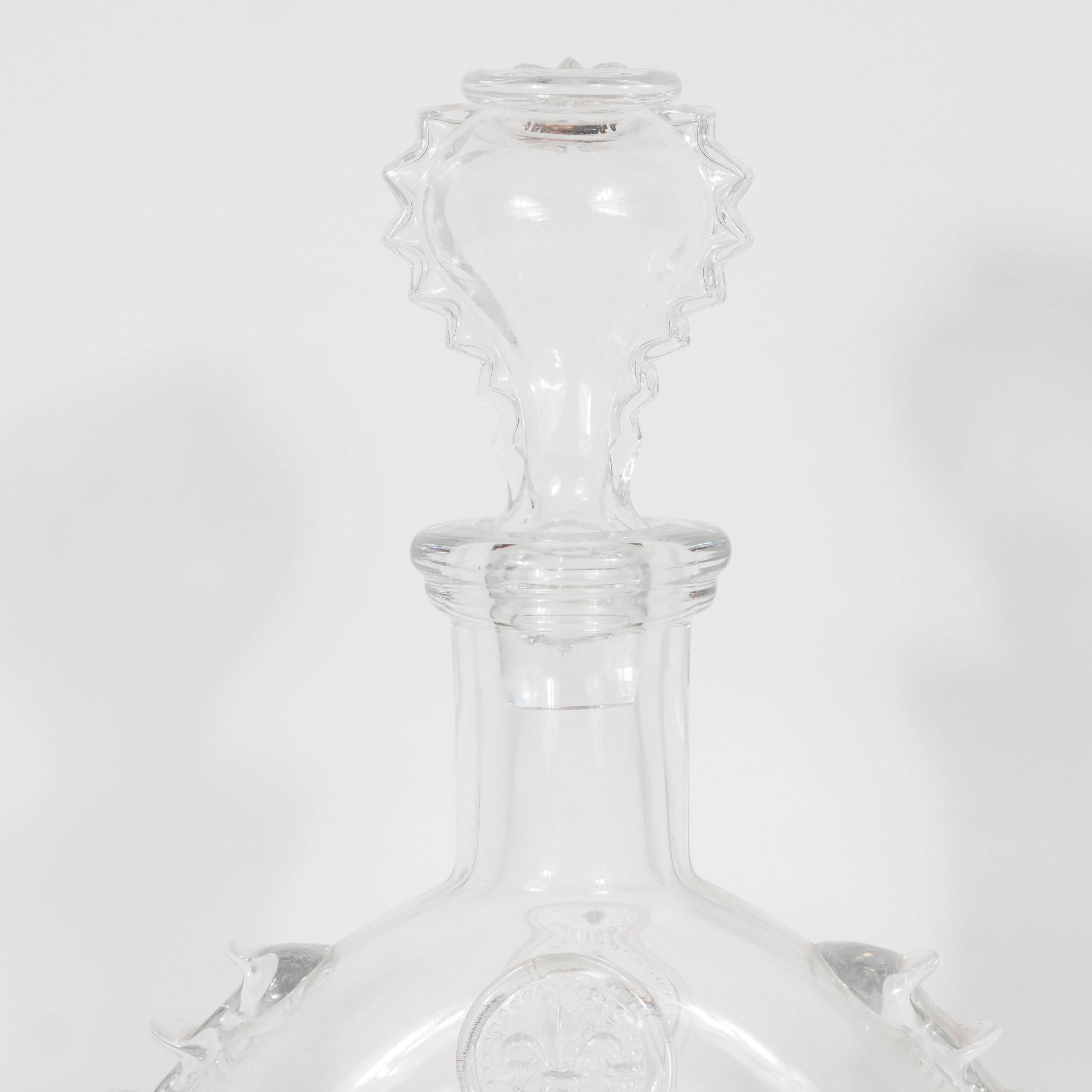 A vintage Baccarat crystal Louis XIII decanter. A bulbous, donut-form features spike detailing on either side and fleur-de-lys embossings throughout, as well as on top of the lid/cap. This piece is signed 