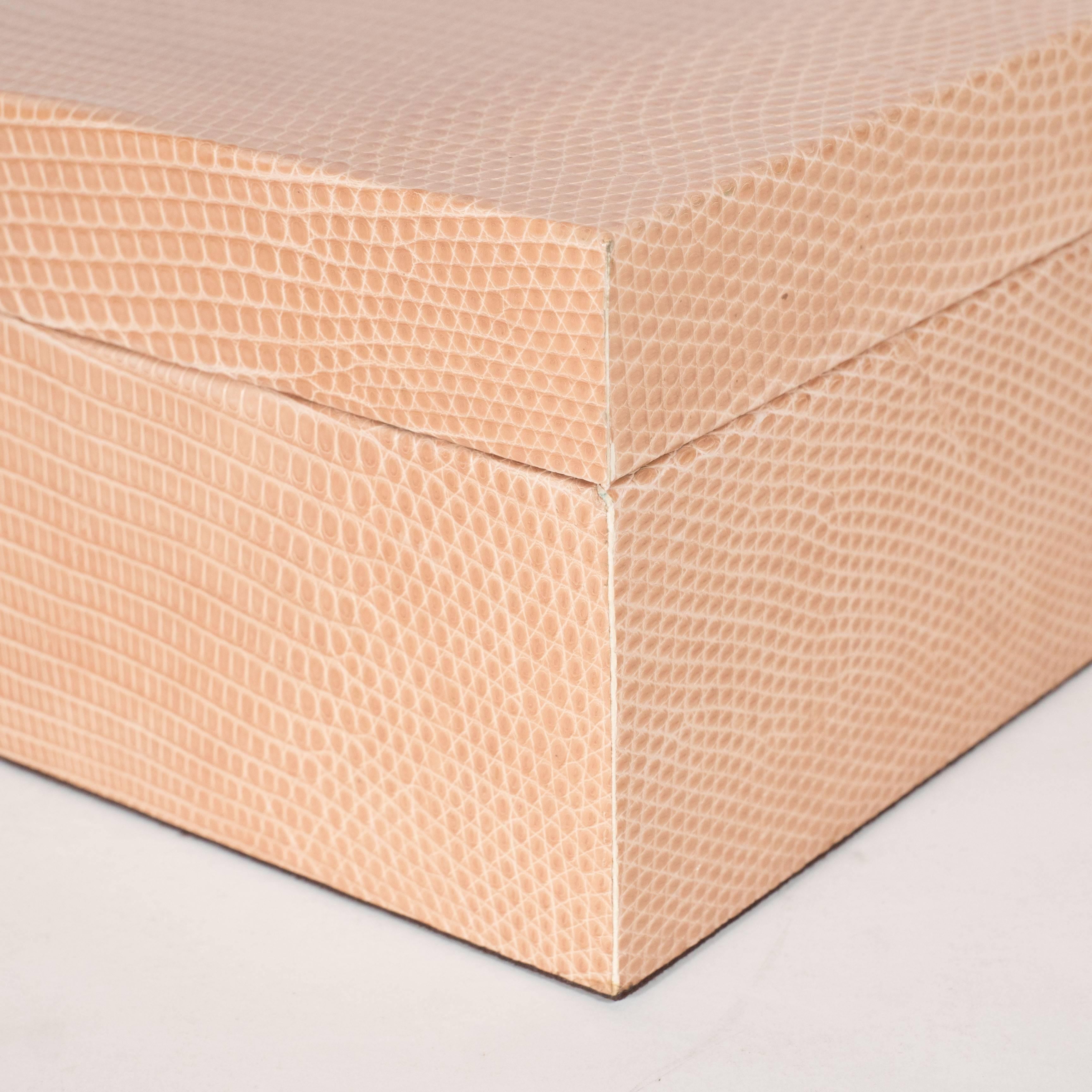 Une boîte d'allumettes moderniste en peau de lézard avec un couvercle amovible. L'intérieur est revêtu d'une ultra-suède brun foncé et le couvercle est soutenu par des socles en bois situés sur deux côtés opposés de la base. Parfait pour ranger des