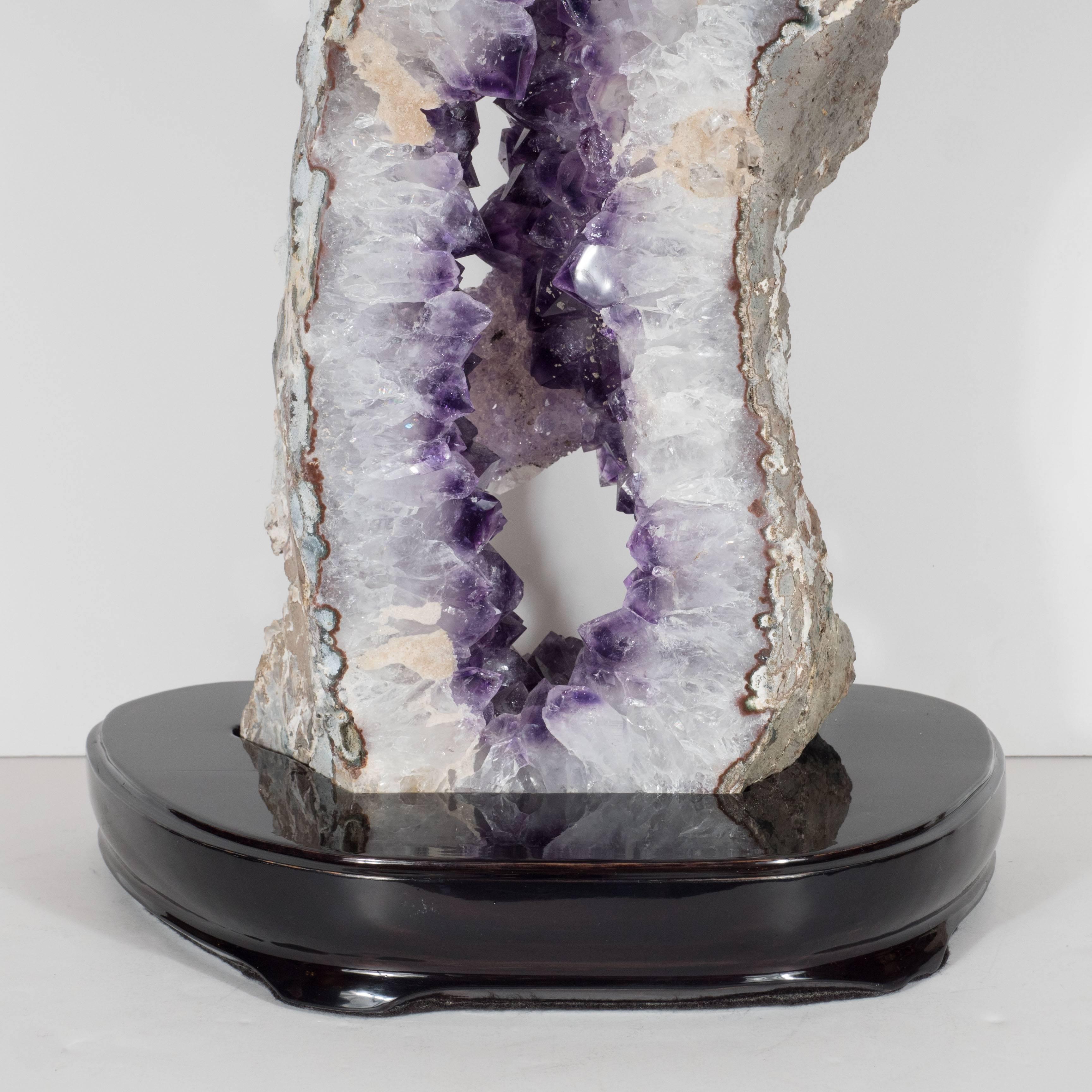 This gorgeous rock specimen of amethyst sliced geode is mounted on a ebonized walnut base. This is a stunning wonder of nature that would be an excellent addition to any style of decor. It is in excellent condition.

Brazil, 21st