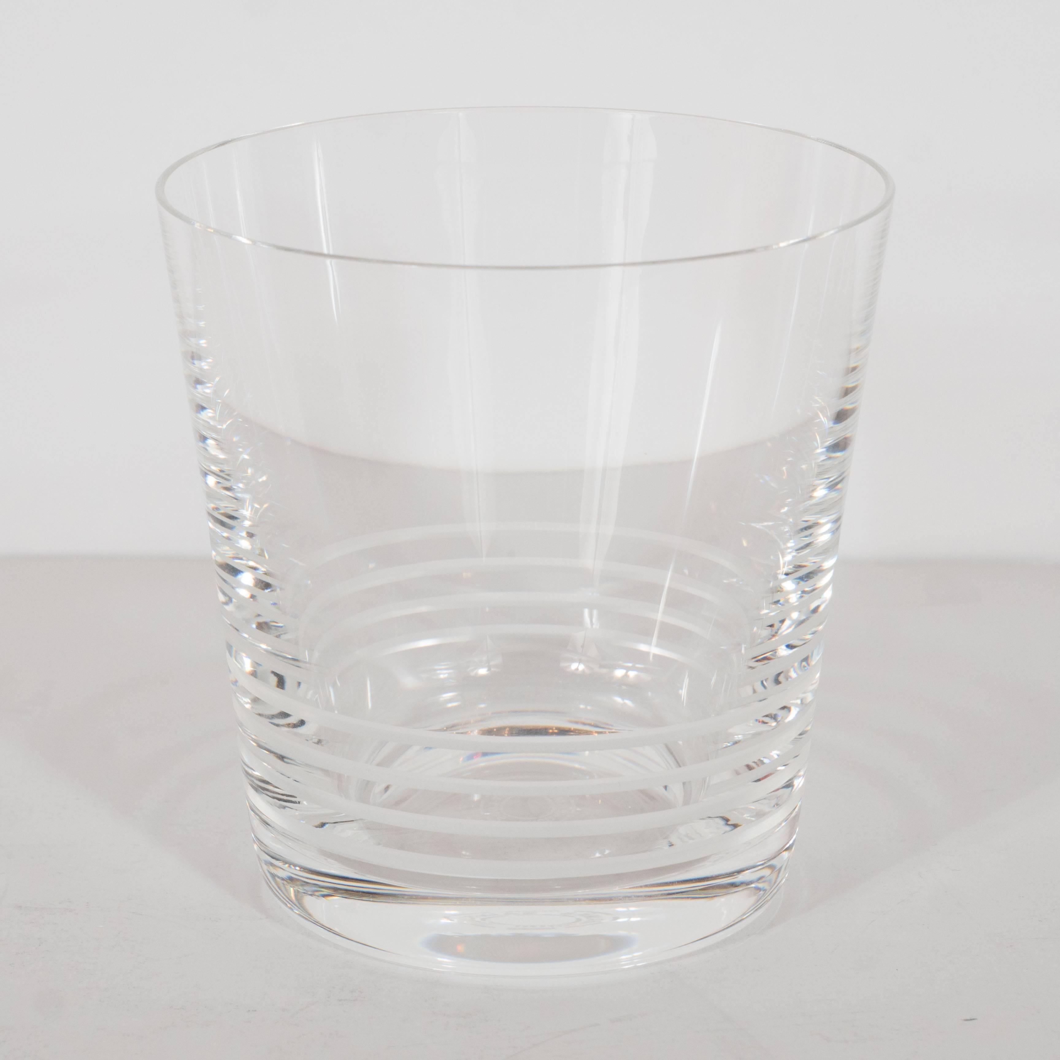An exquisite set of 12 Attelage series crystal tumblers by Saint Louis for Hermes. Weighted bases support a slightly tapered form. Circular etchings along the bottom outer perimeter of the glass adorns each. Stamped 