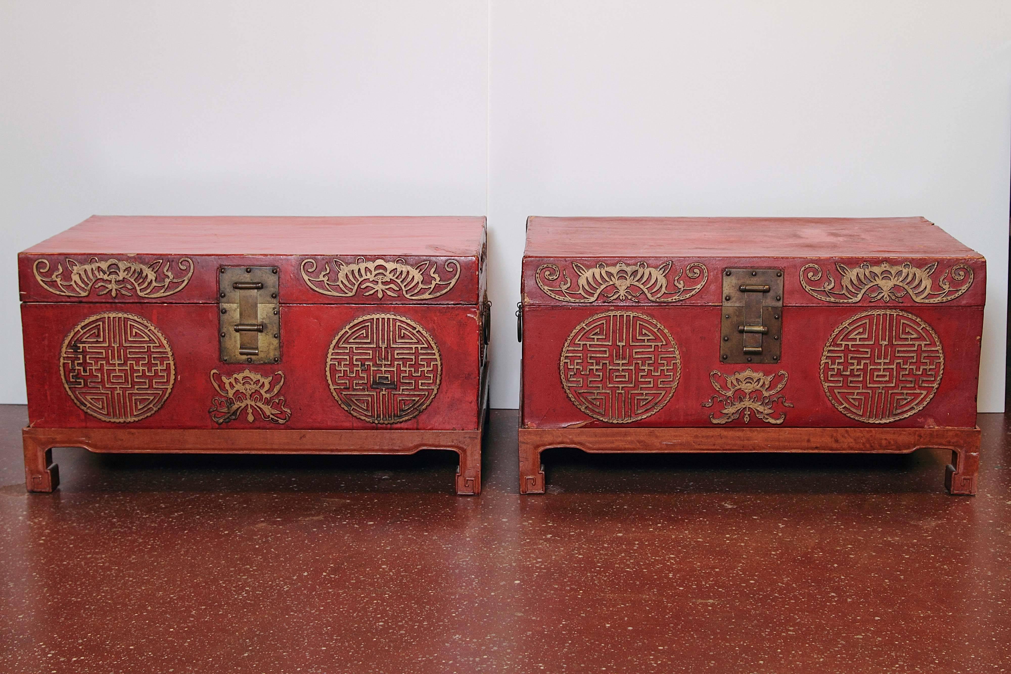 Pair of early 20th century Chinese red lacquered leather trunks on stands.
