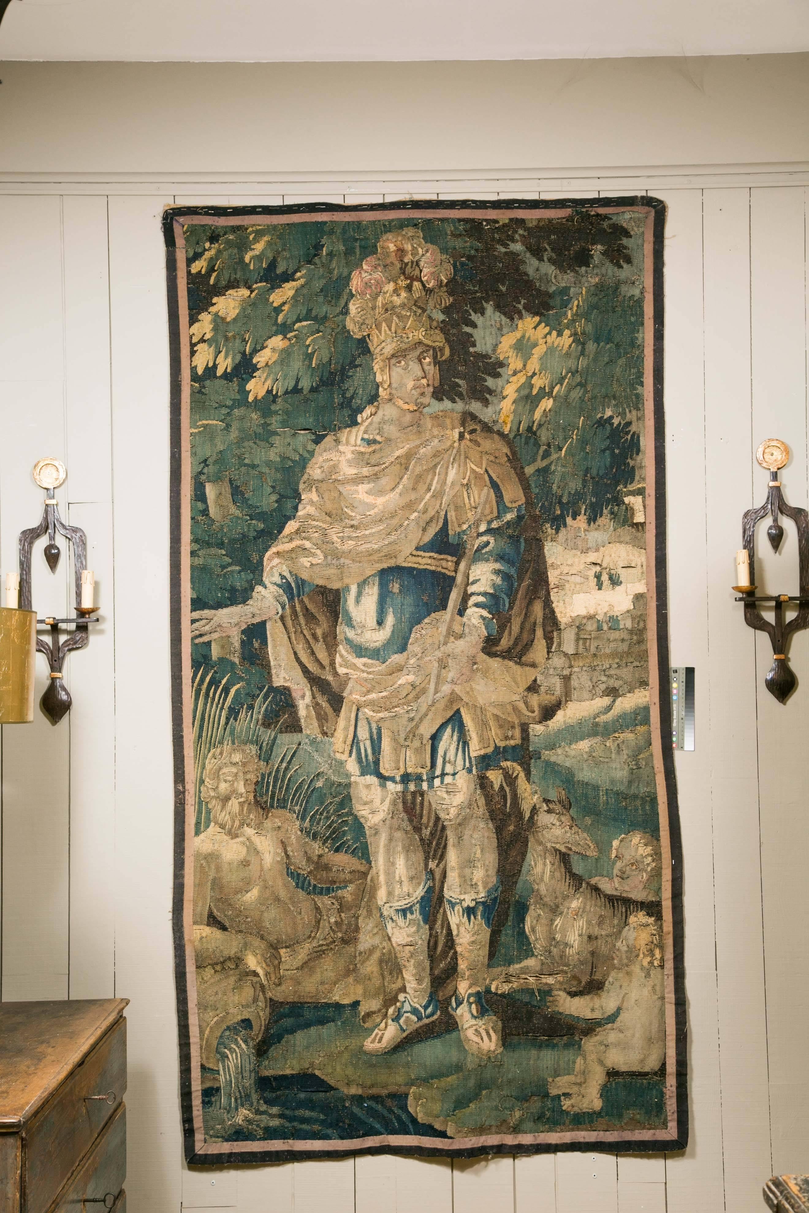 An early 18th century (possibly late 17th) vertical flemish tapestry.

Polychrome scene depicting a dressed knight in a forest scenery with the mythology's figure of Neptune in the bottom part.

Very good condition. Unframed.