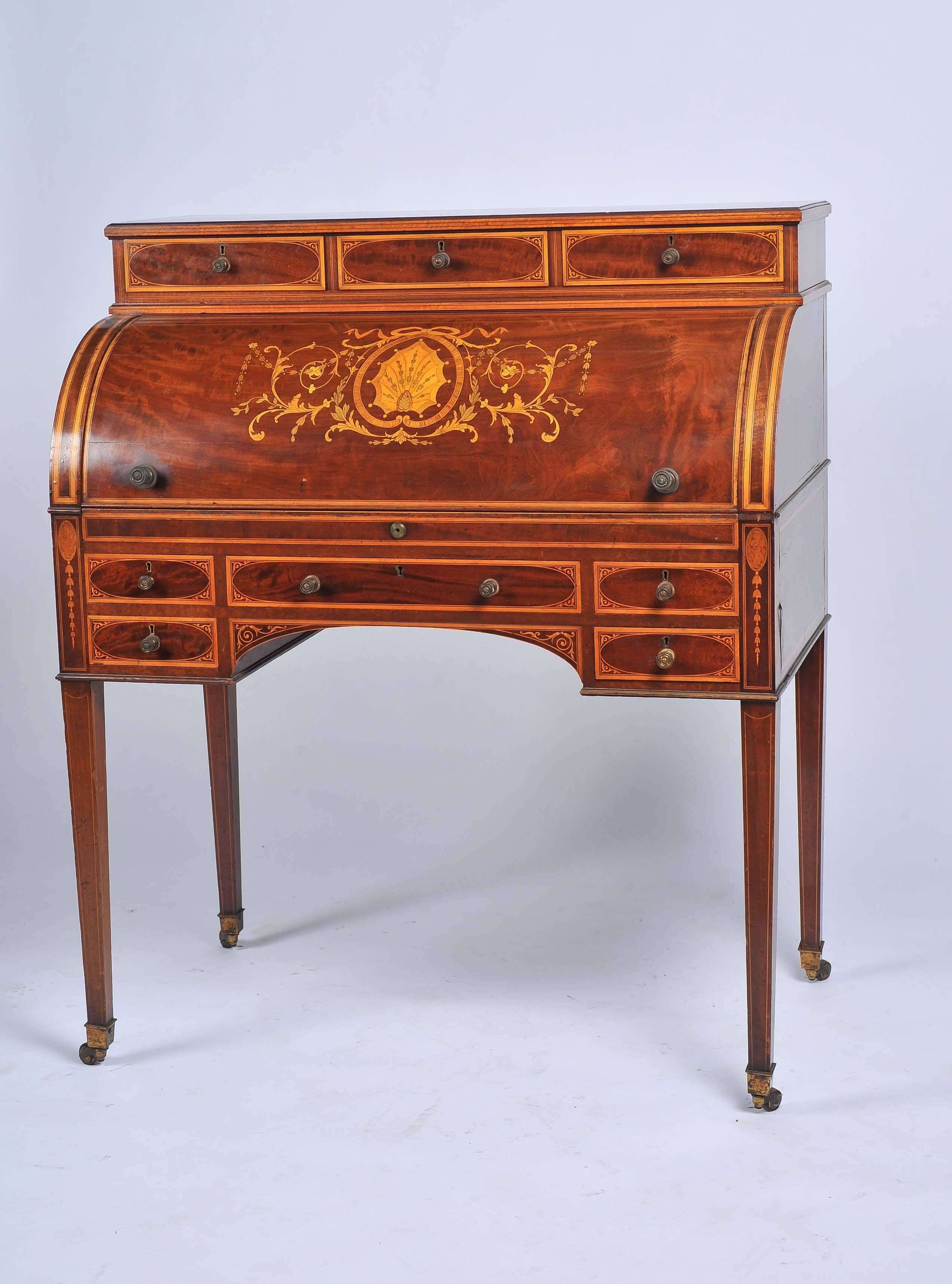 A very good quality Edwardian period mahogany inlaid cylinder desk, having compartments within, a sliding writing tablet, five mahogany lined drawers and raised on square tapering legs.